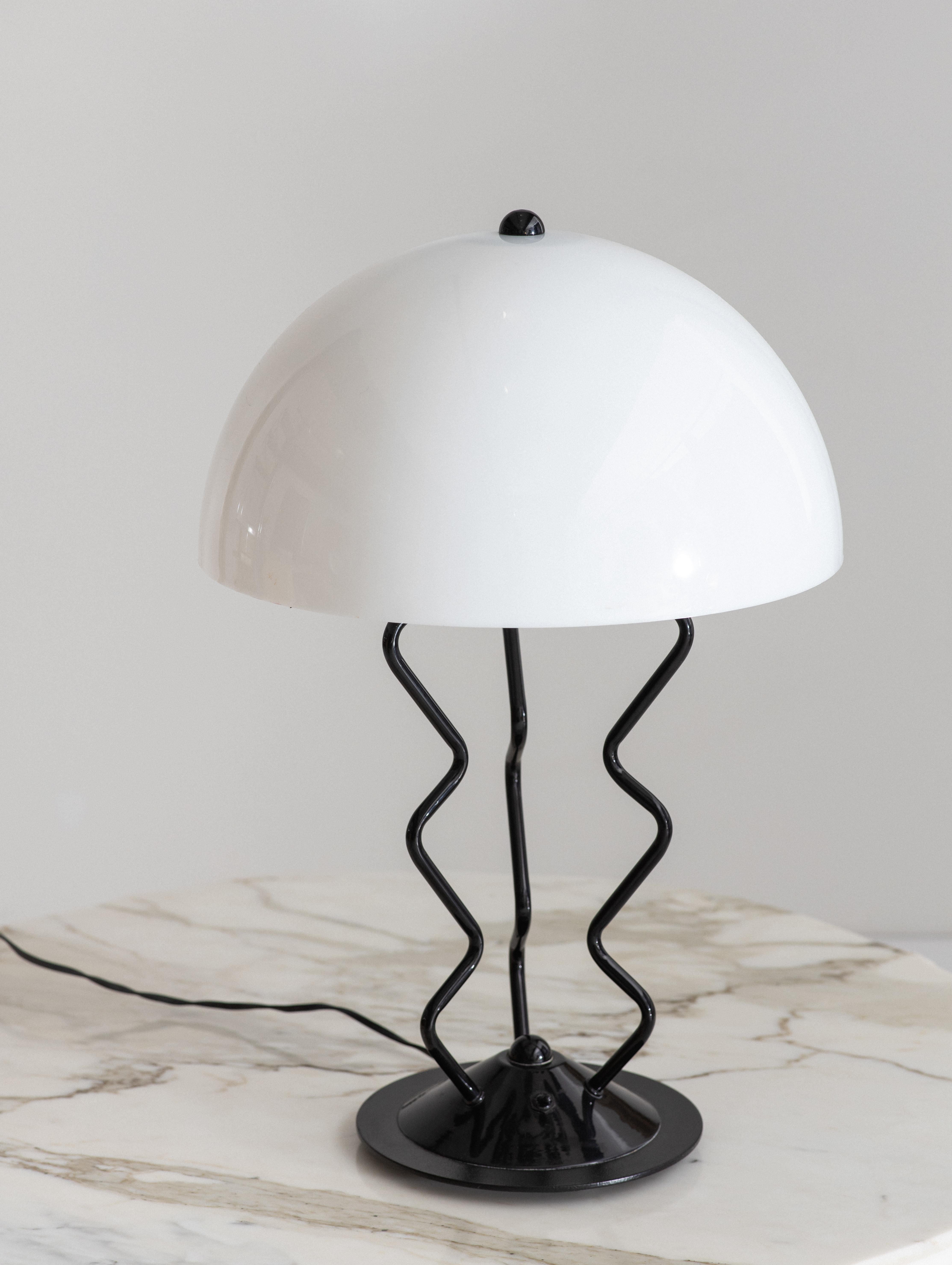 Memphis style gloss black metal table lamp with white acrylic dome shade. Fantastical form suggestive of a jellyfish. On off switch at base.