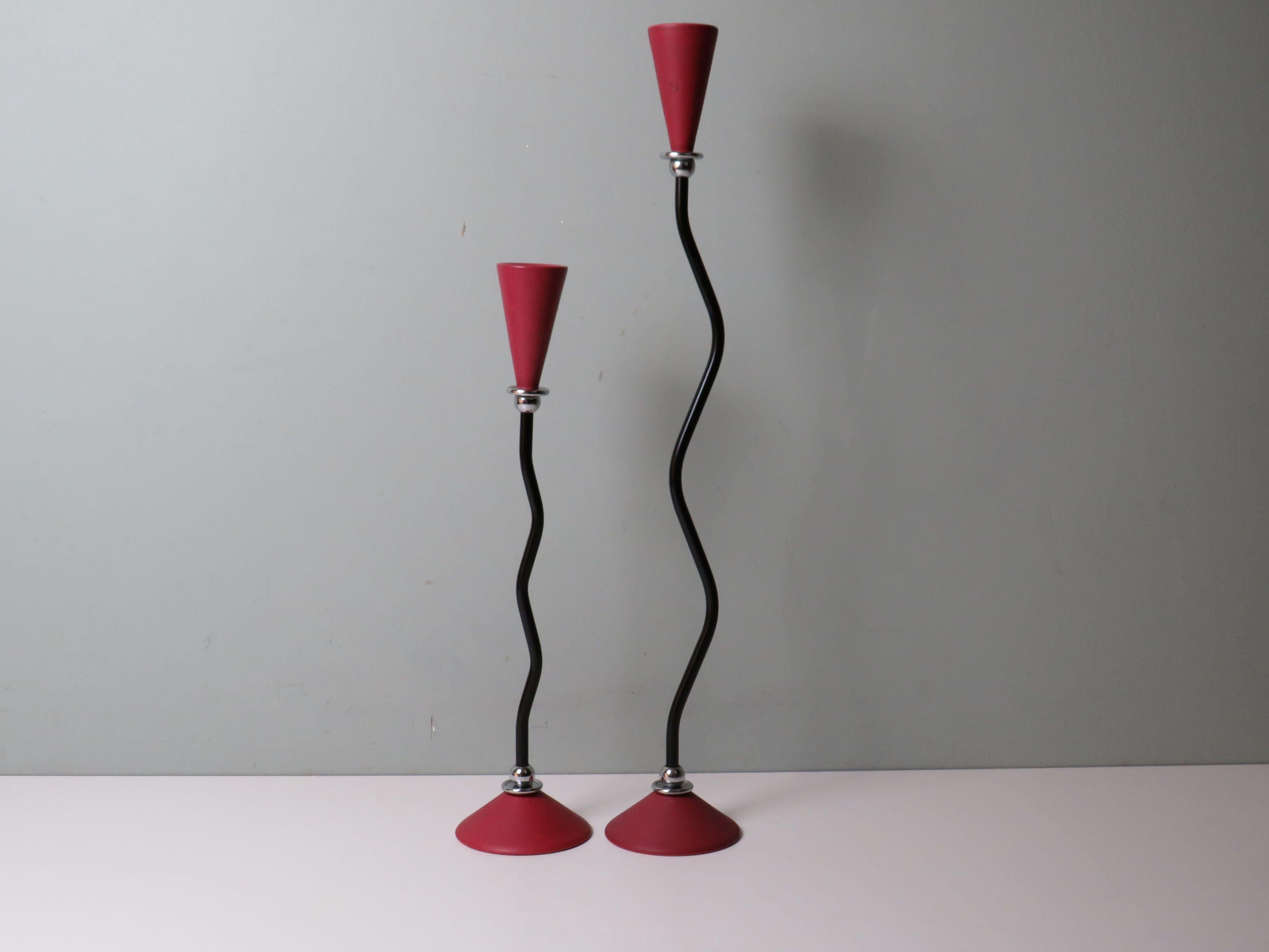 A sculptural pair of Memphis-style candleholders, embodying the bold creativity of 1980s postmodern design. The matte dark red/burgundy ceramic elements contrast elegantly with the curved black metal stems and chrome connectors, producing a striking