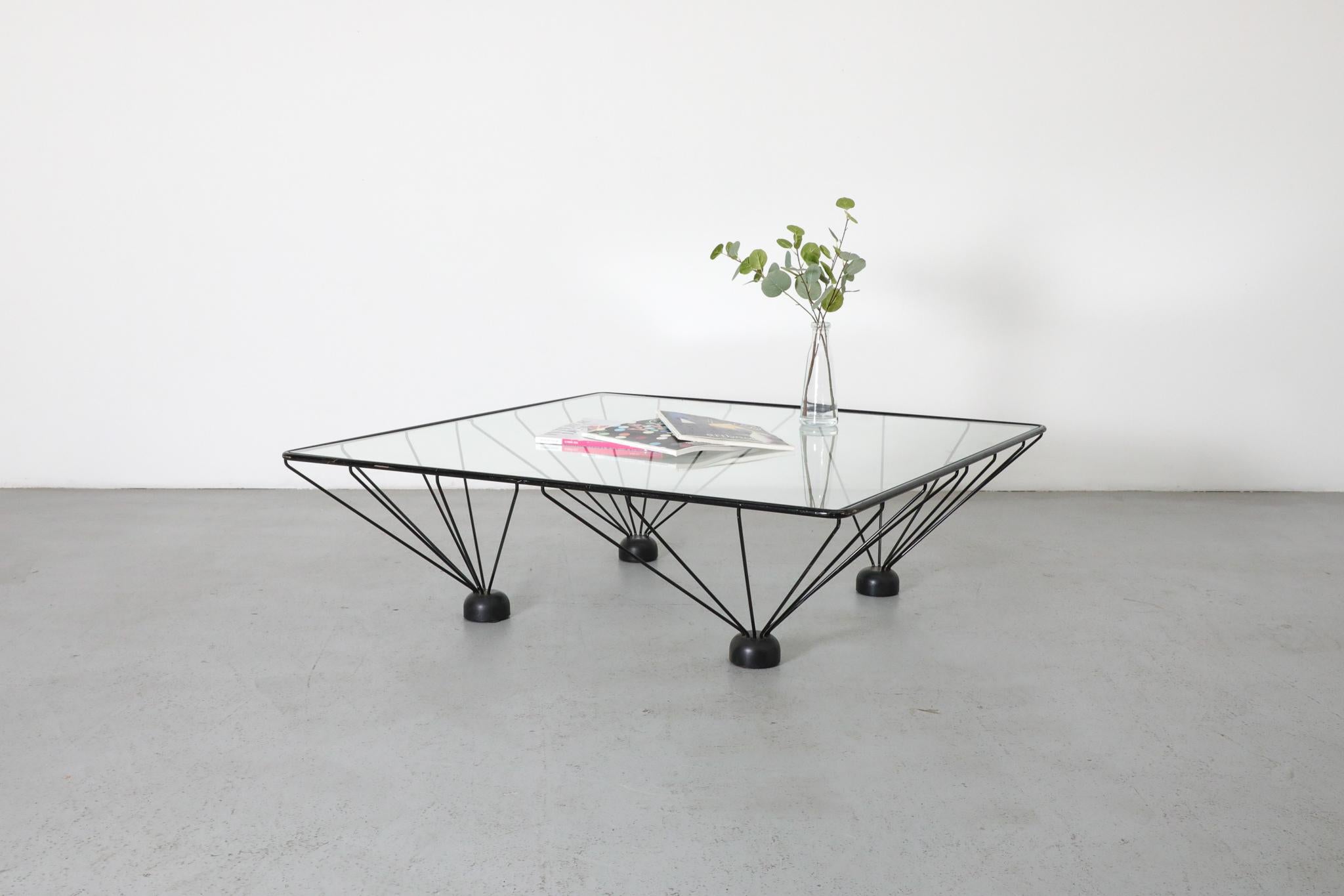 Mesa de centro piramidal estilo Memphis, inspirada en Ettore Sottsass, con estructura arquitectónica de metal esmaltado. En estado original con arañazos visibles y desconchones en el cristal. El desgaste es acorde con su edad y uso.