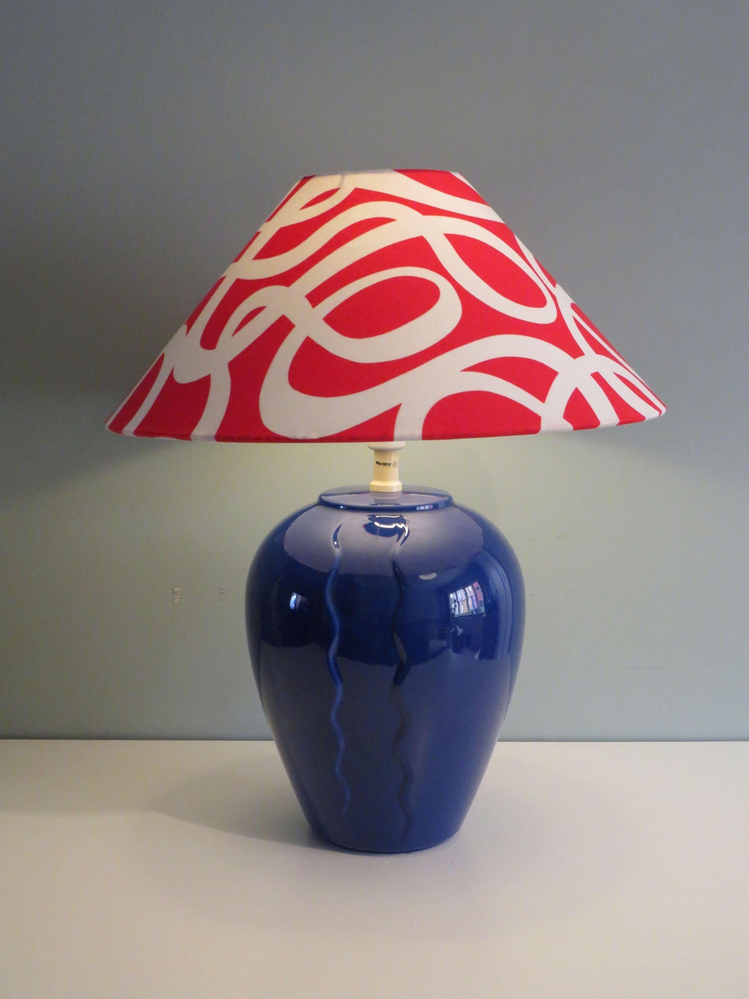 Blue ceramic table lamp in Memphis style by Ikea, 1980s. Label is located at the bottom of the ceramic table base.
The intense blue ceramic base has a custom-made lampshade in red-white fabric by Erika Pekkari for Ikea from 2006. The table lamp has