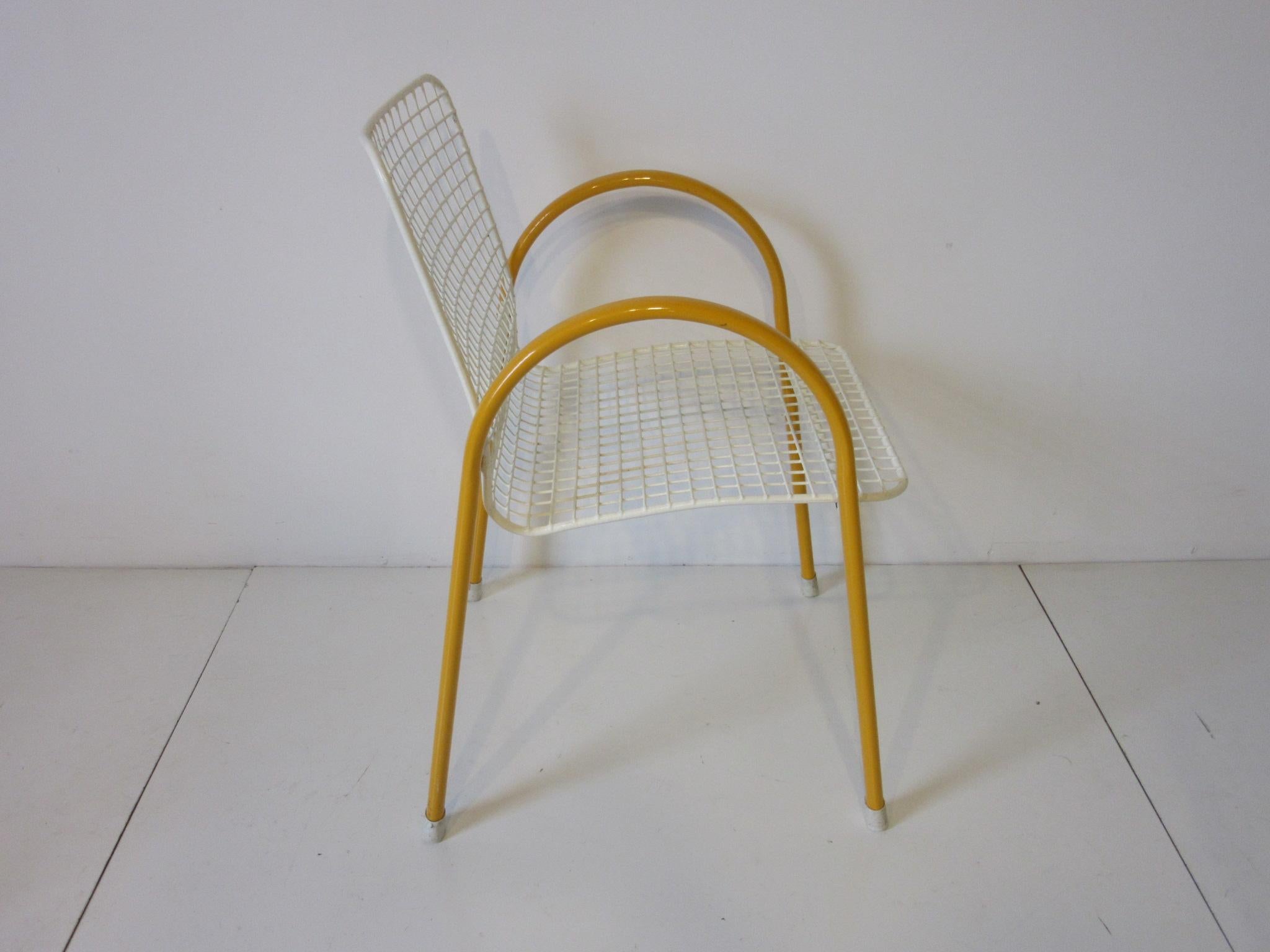 A set of four white wire seated chairs with yellow one piece arching arms and legs with rubber end caps for feet. These chair stack nicely and have a coated finish for protection, retains the manufactures label made in Italy by the EMU furniture