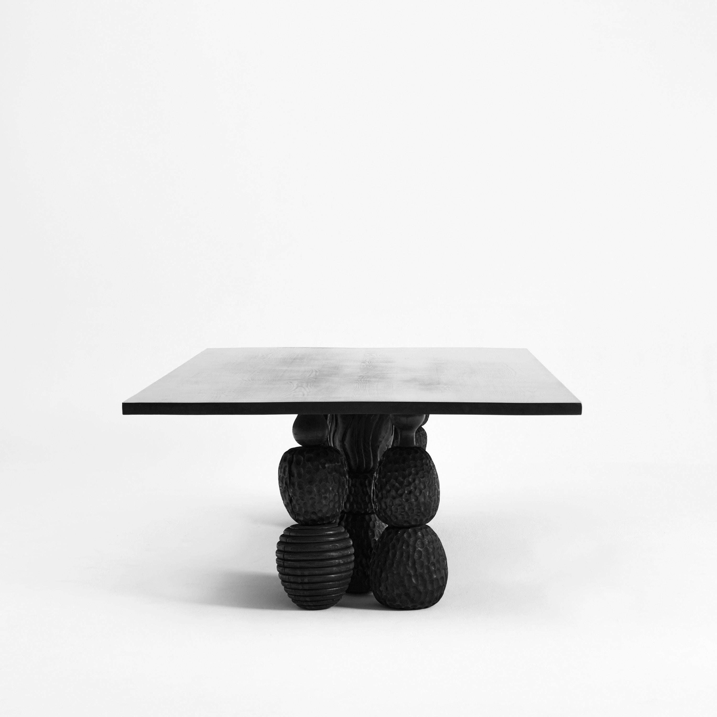 TABLE À DINER MENINA, conçue en 2024.

Cette table de salle à manger est fabriquée en châtaignier massif verni noir avec 6 pieds ornementaux. Chaque pied est formé de différentes pièces empilées, ciselées à la main et de textures