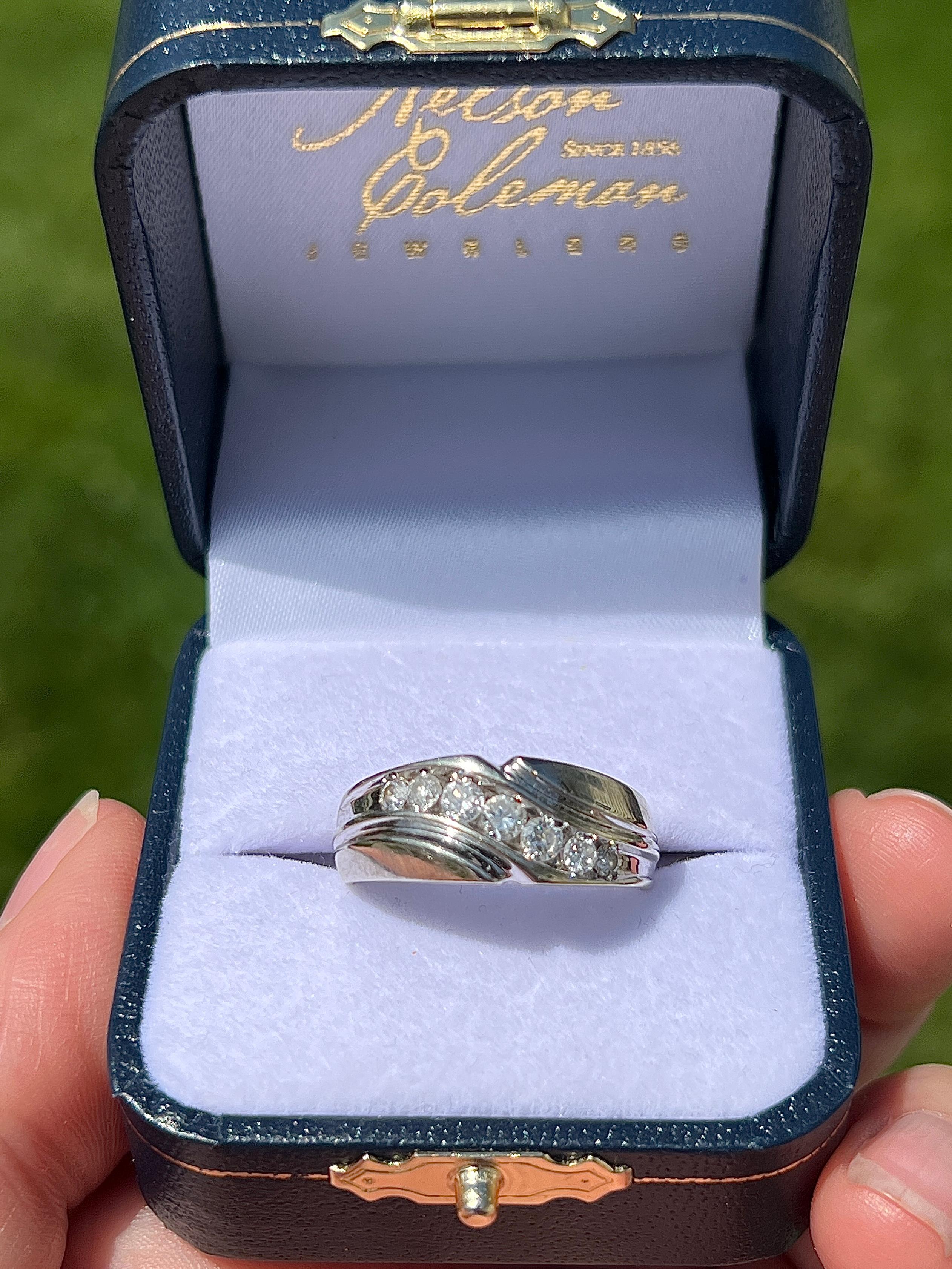 Ein zeitgenössischer Ehering für Männer aus 14 Karat Weißgold mit sieben runden Brillanten, die fachmännisch in einer anmutigen diagonalen Anordnung gefasst sind, mit insgesamt ca. 0,51 Karat, Farbe I und Reinheit I1. Die schlanke Kanalfassung