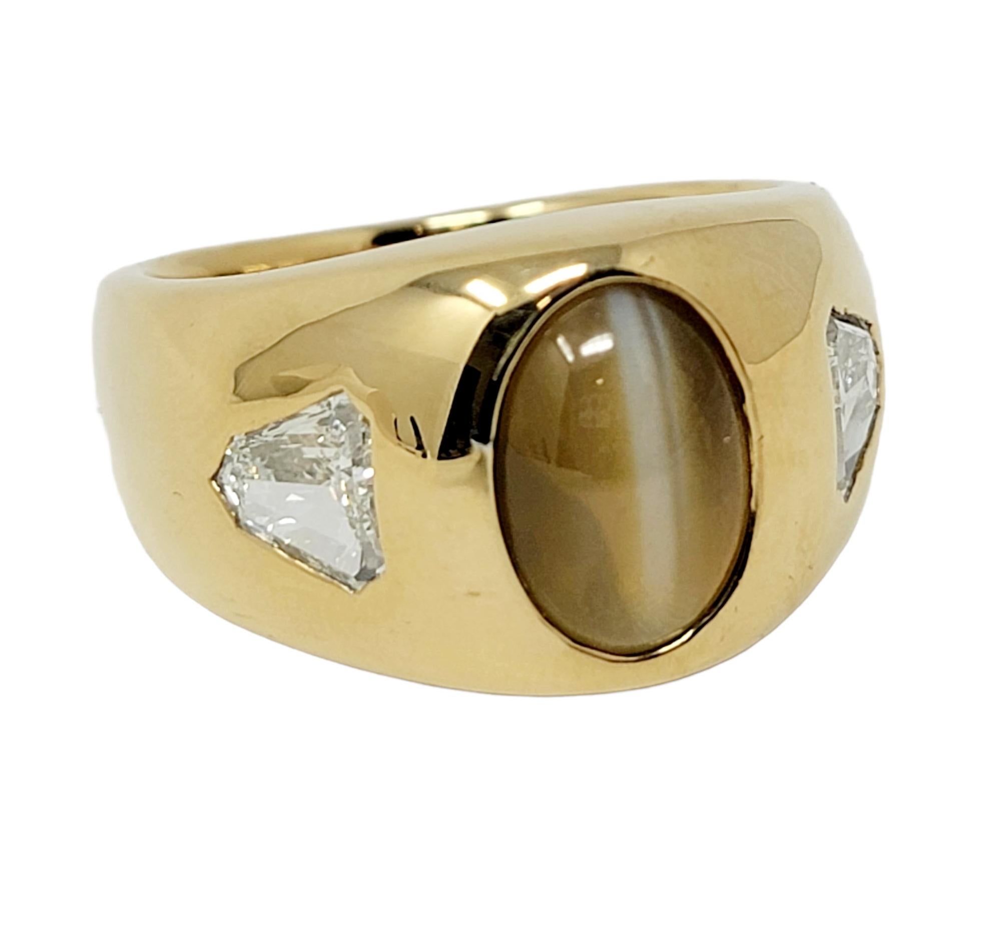 This bold, contemporary cat's eye chrysoberyl and diamond band ring will not go unnoticed! The incredible 8.86 carat oval cabochon chrysoberyl stone is bezel set in 18 karat yellow gold at the center of the piece and arranged in a vertical layout.