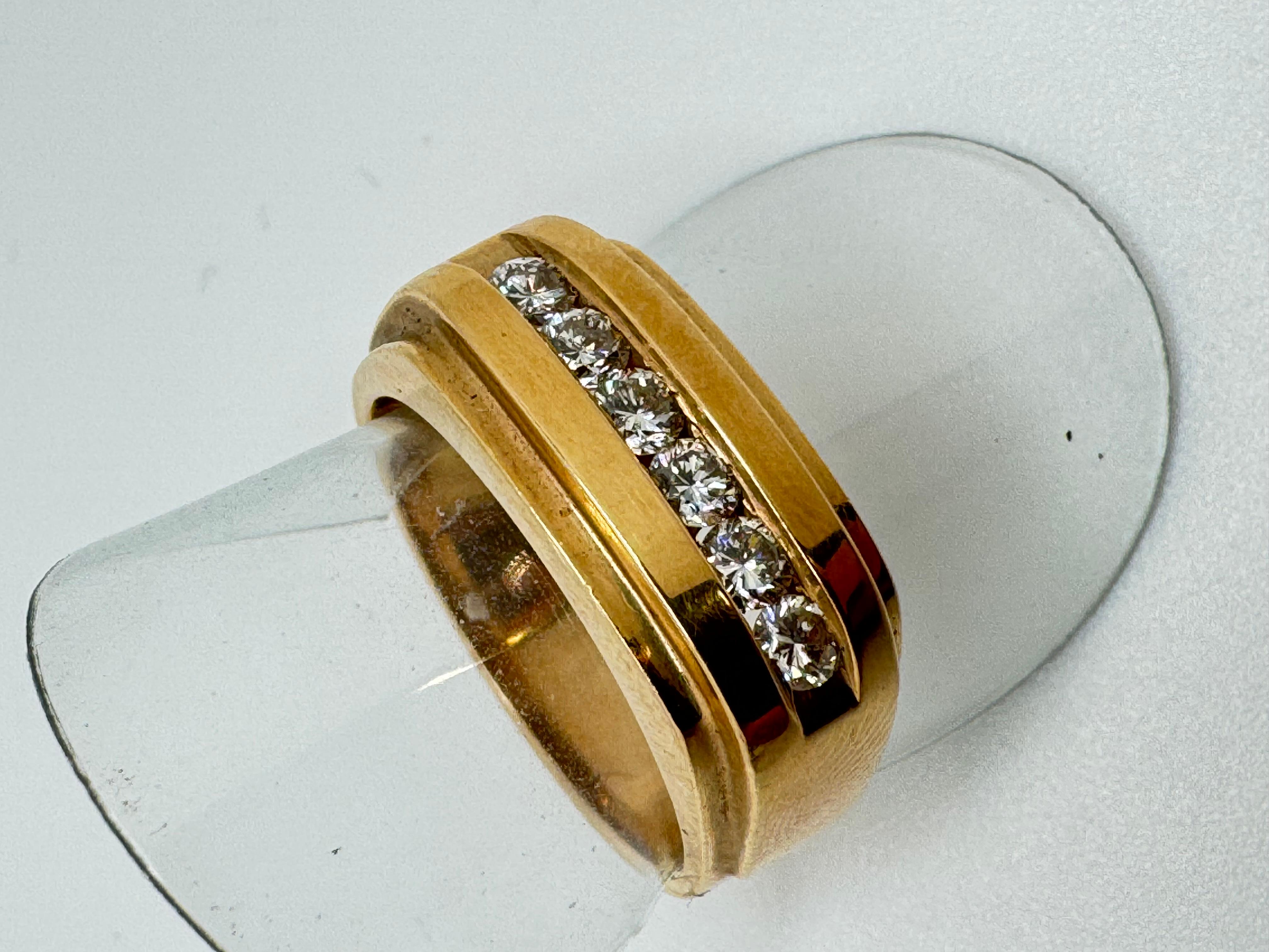 Realizzato in ricco oro giallo 14 carati, questo anello da uomo presenta un design elegante e senza tempo con un tocco audace. In un canale lineare e pulito sulla parte superiore sono incastonati sei diamanti rotondi a taglio brillante, per un peso