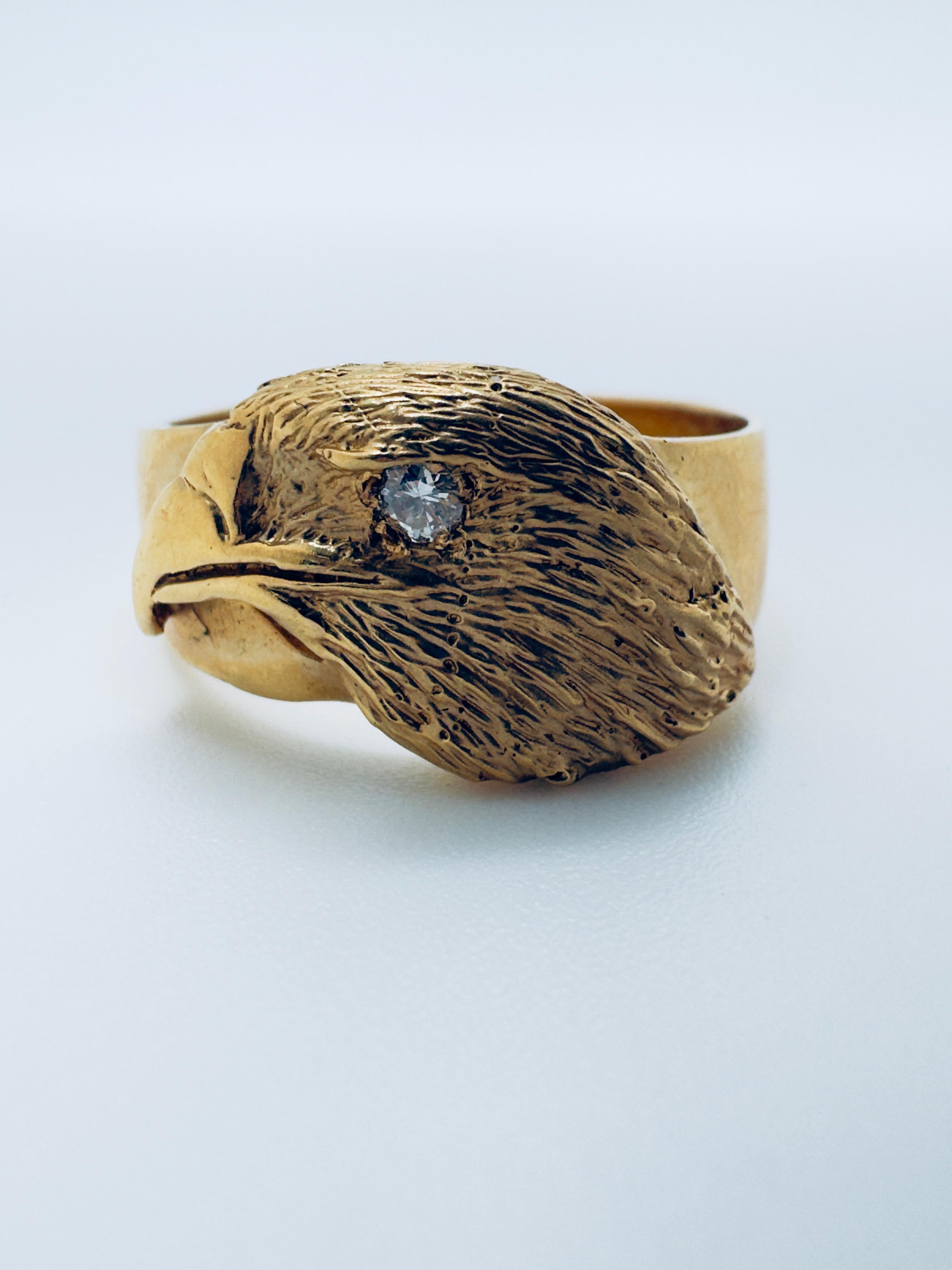 This bold men’s ring is crafted in 14 karat yellow gold and features a striking eagle head design, symbolizing strength and vision. The eagle’s eye is set with a round diamond weighing approximately 0.08 carats, graded SI1 for clarity and G-H for