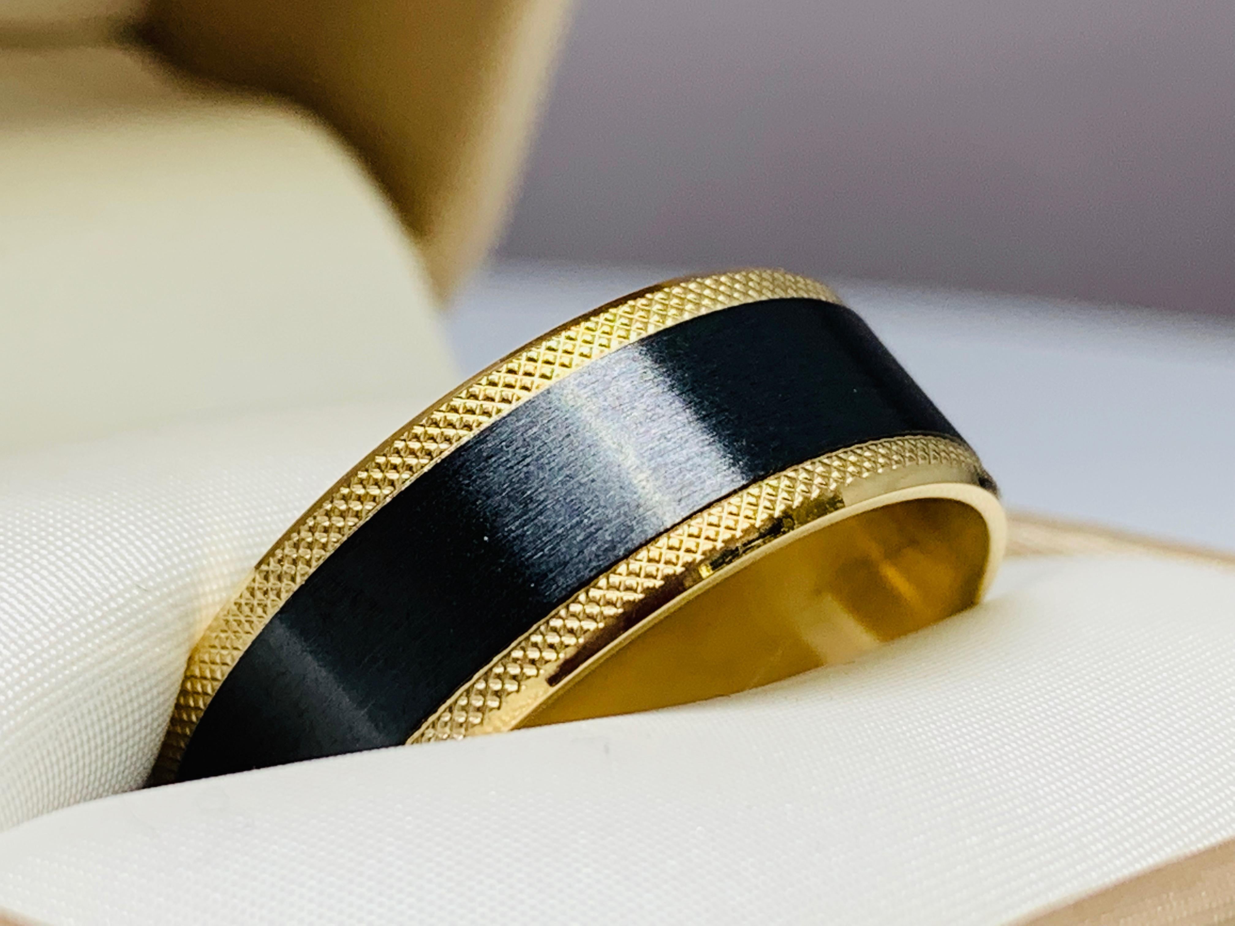 This Benchmark wedding band is both classic and handsome! This ring is crafted out of both 14K yellow gold and black titanium. The edges of the ring are yellow gold with a beaded detail and the center of the ring is black titanium with a satin