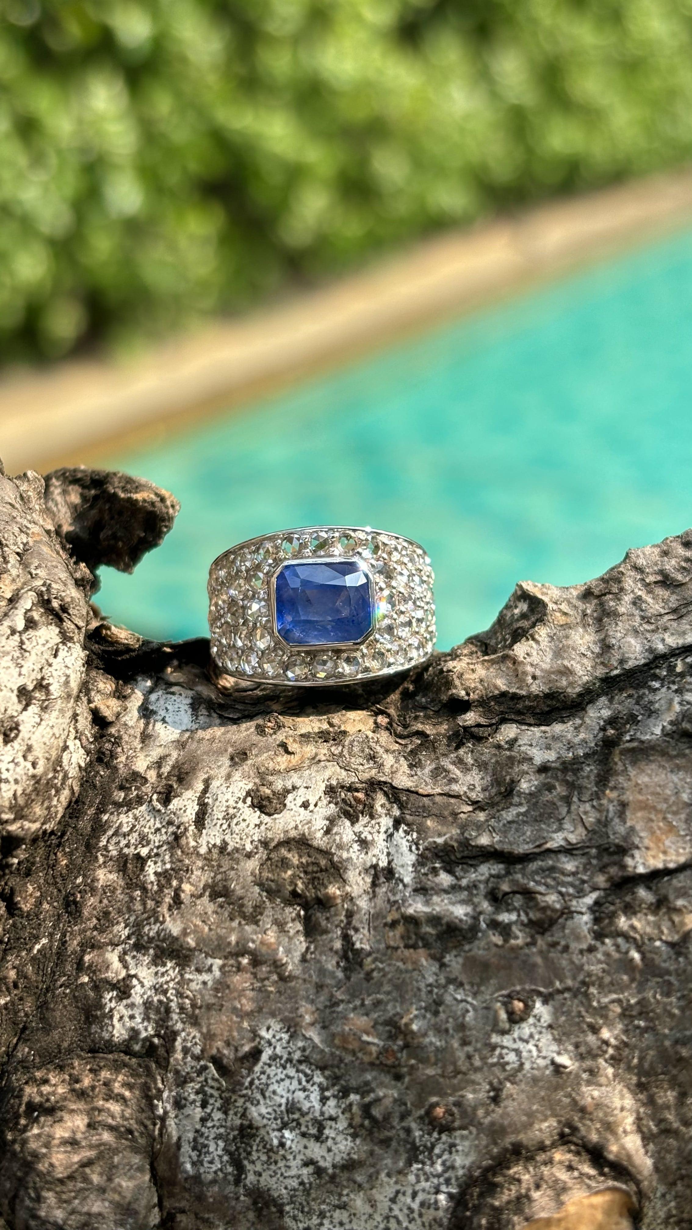 Presenting a lustrous, gemstone ring for men,  that will win over anyone’s heart with its sheer beauty and sophistication. This stunning piece showcases a majestic, emerald-cut Sapphire as its centerpiece, radiating a breathtaking luster and