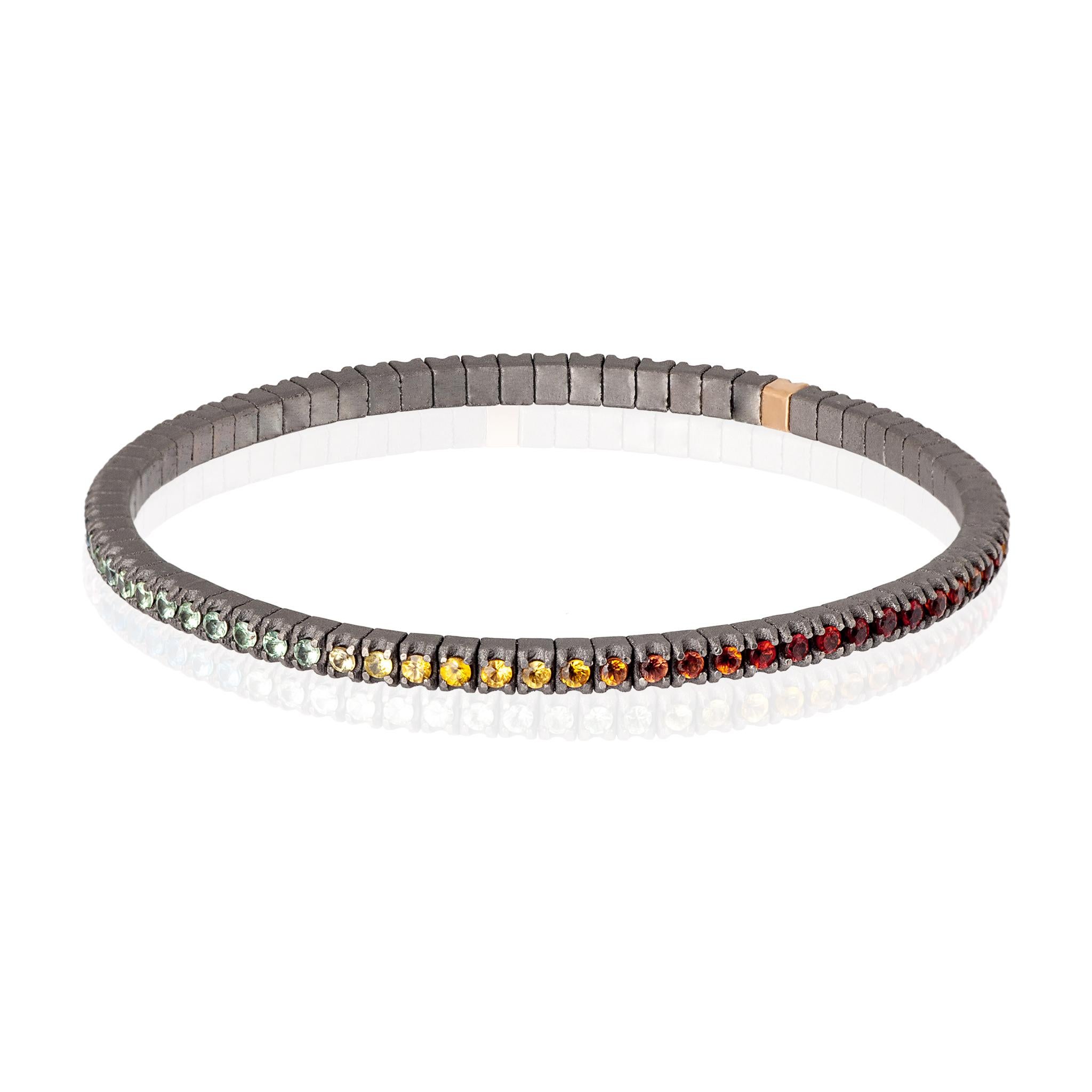 Men's Line Loop bracelet in titanium and multicolor sapphires (ct. 2.15 approx.). The structure consists of an unbroken row of 3-point diamonds set on titanium griffes and one in 18kt red gold placed side by side on an elastic link. This bracelet