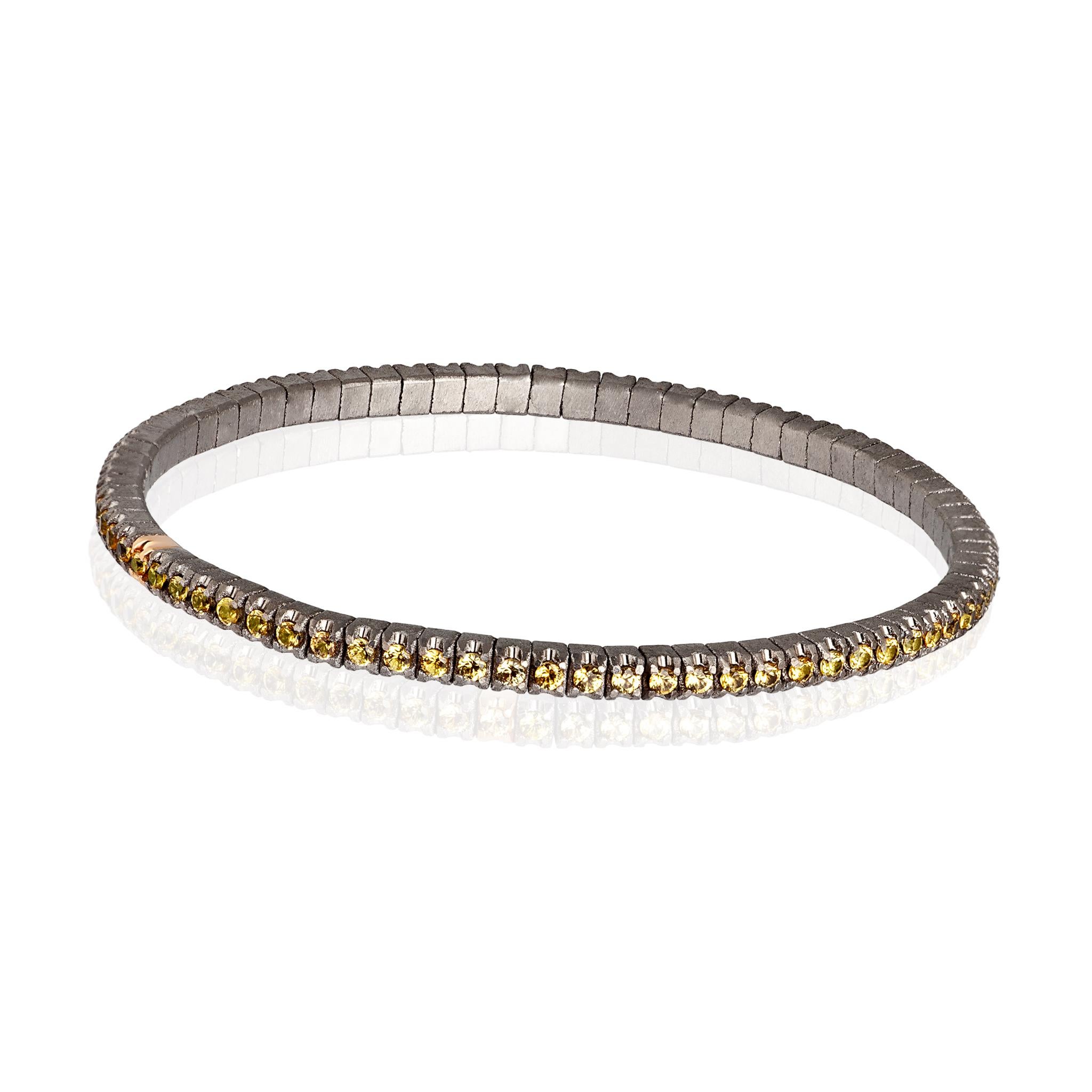 Men's Line Loop bracelet in titanium and yellow sapphires (ct. 2.15 approx.). The structure consists of an unbroken row of 3-point diamonds set on titanium griffes and one in 18kt red gold placed side by side on an elastic link. This bracelet