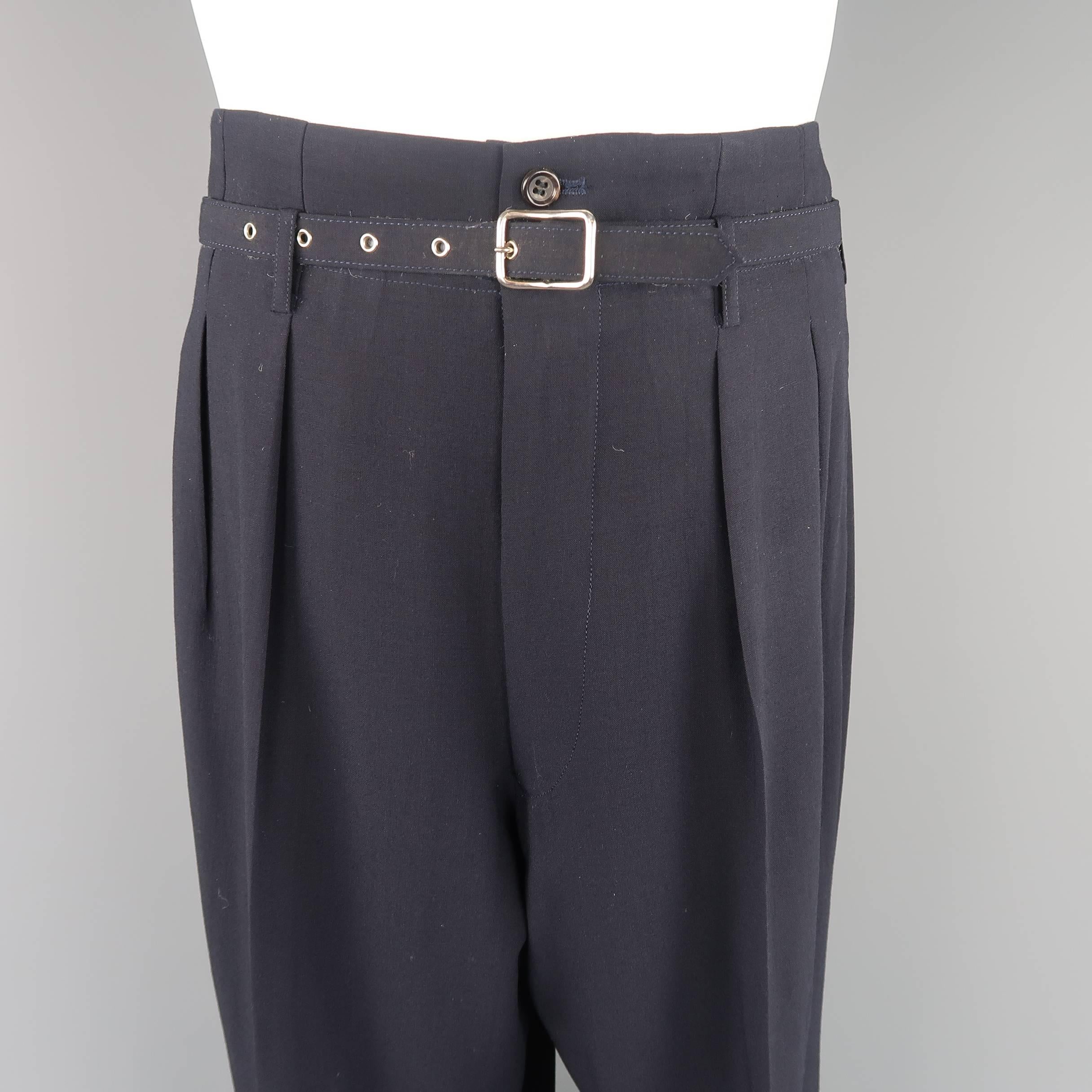 COMME des GARCONS HOMME PLUS dress pants come in navy blue wool with a high rise, pleated front, wide tapered leg, cuffed hem, and matching fabric waist belt. Belt liner cracking and worn out. Pants in excellent condition. As-is. Made in Japan.
