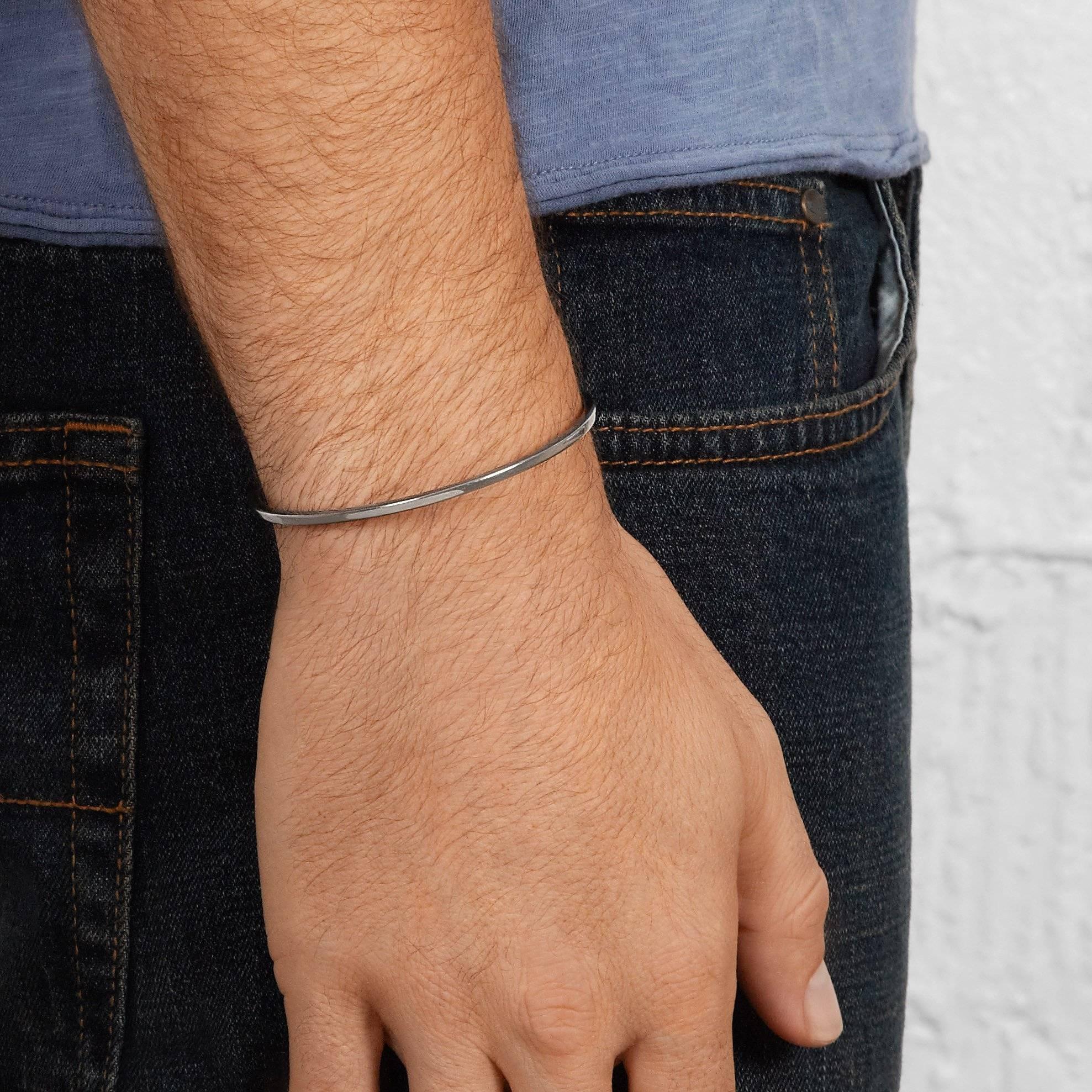 This simple men's cuff bracelet is crafted in oxidised sterling silver and accented with solid 18-carat rose gold tiles at each end. 

Handmade in London. Hallmarked 925 Allison Bryan London.