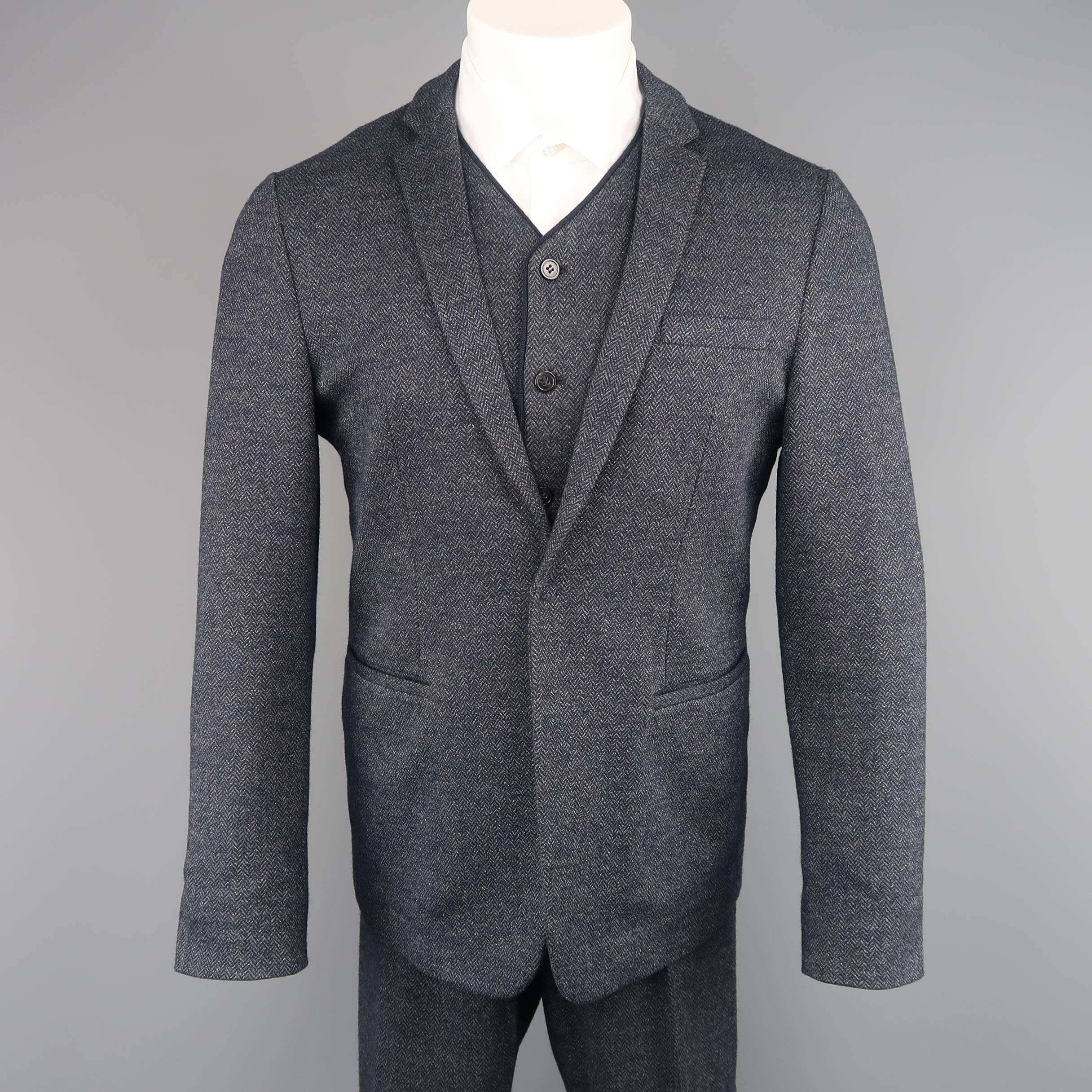 Three piece EMPORIO ARMANI suit comes in a navy blue Herringbone print wool cotton knit felt and includes a singe breasted, notch lapel sport coat with single hidden snap closure, V neck vest, and matching flat front trousers. Made in Italy.
 
Good