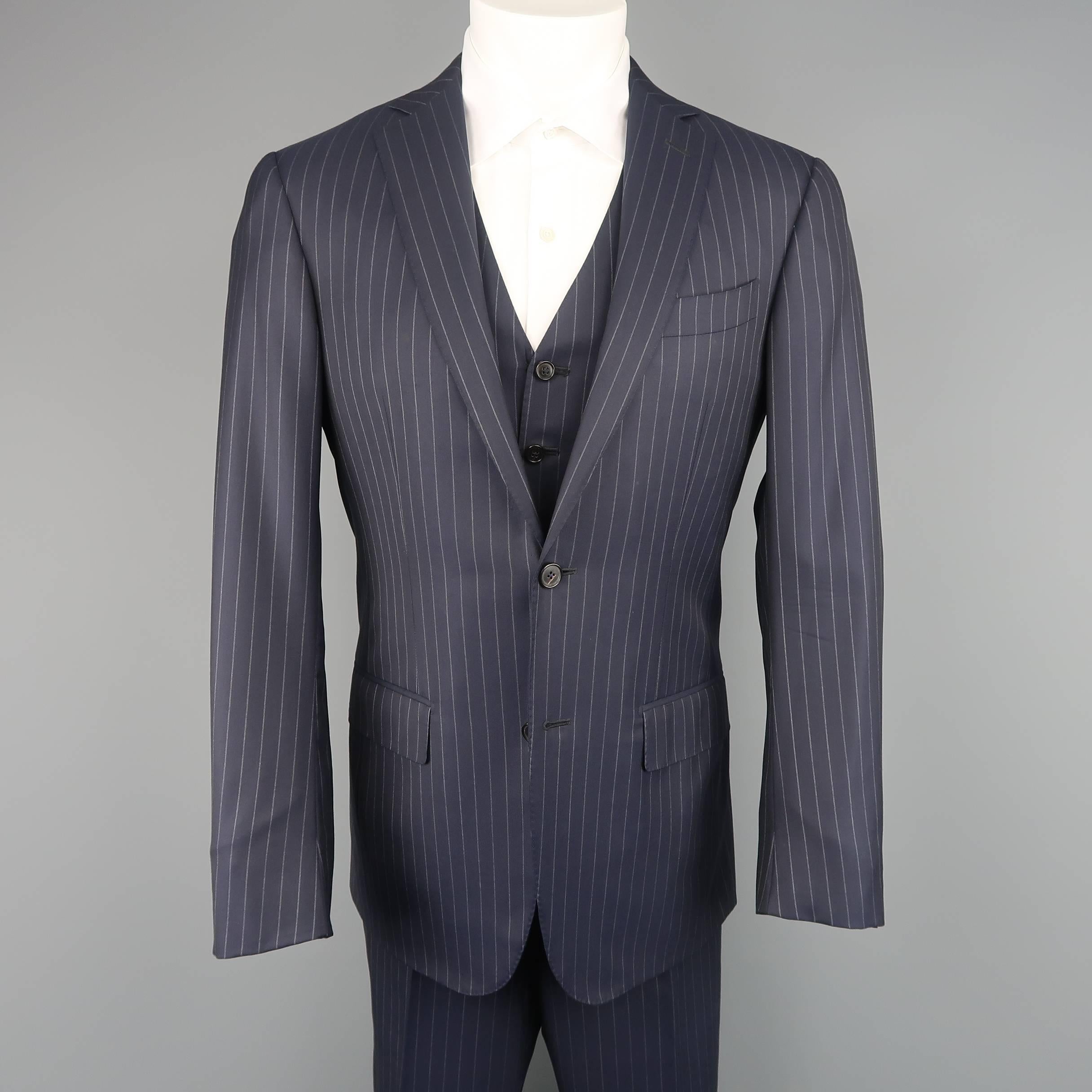 Three piece ERMENEGILDO ZEGNA comes in navy and gray pinstripe wool and includes a single breasted, two button, notch lapel sport coat with functional button cuffs, a V neck vest, and matching flat front trousers with cuffed hem. Made in