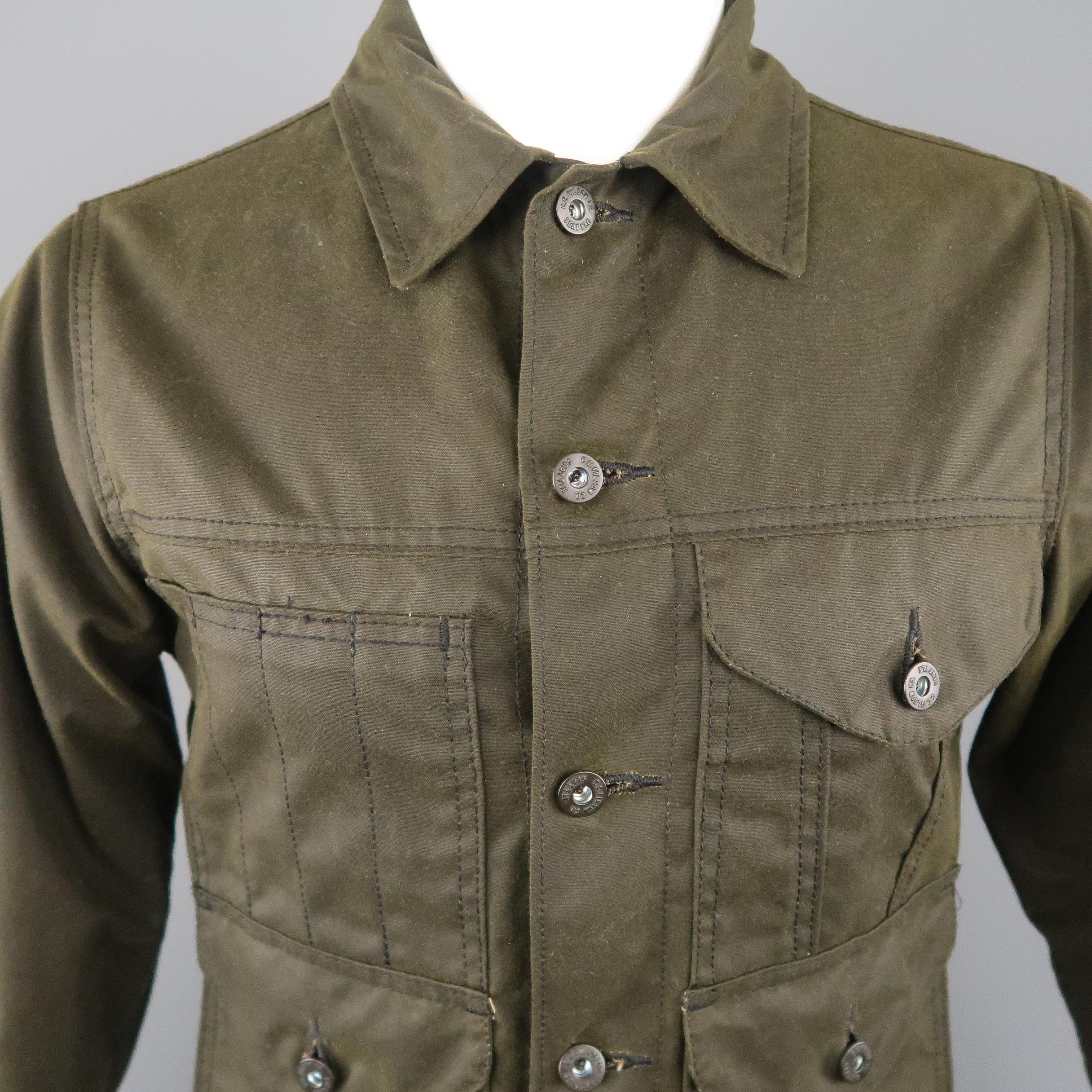 FILSON trucker jacket comes in a distressed olive green waxed cotton with pointed collar, patch flap pockets, patch tool pocket, and waistband tabs. Made in USA.
 
New with Tags.
Marked: XS
 
Measurements:
 
Shoulder: 16 in.
Chest: 39 in.
Sleeve: