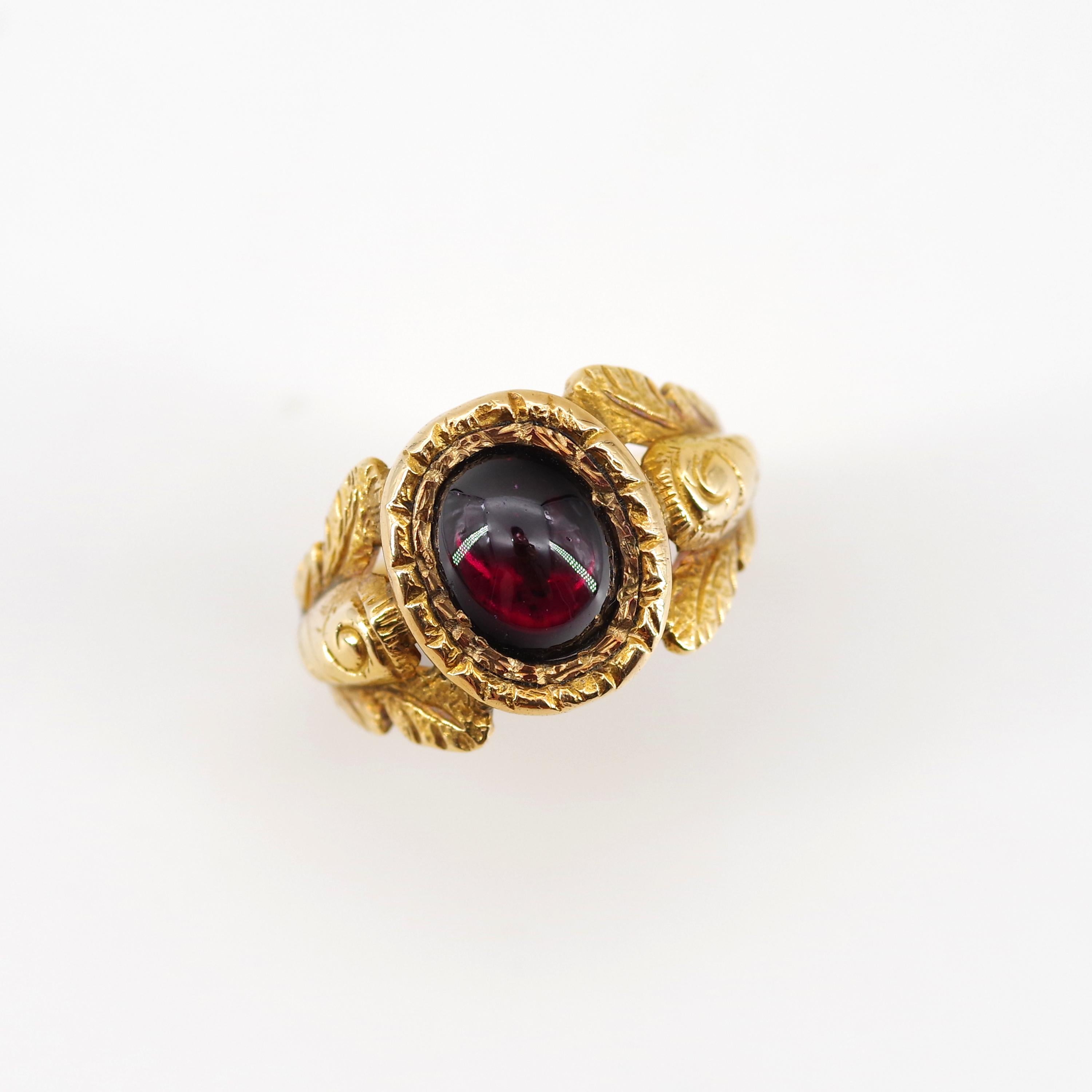 This rare and stunning original Georgian-era men's ring features a 10.5 mm x 9 mm approximately 4-carat pyrope garnet cabochon bezel-set and closed-backed into an elaborately hand-engraved and carved mounting of the richest, most buttery 18K yellow