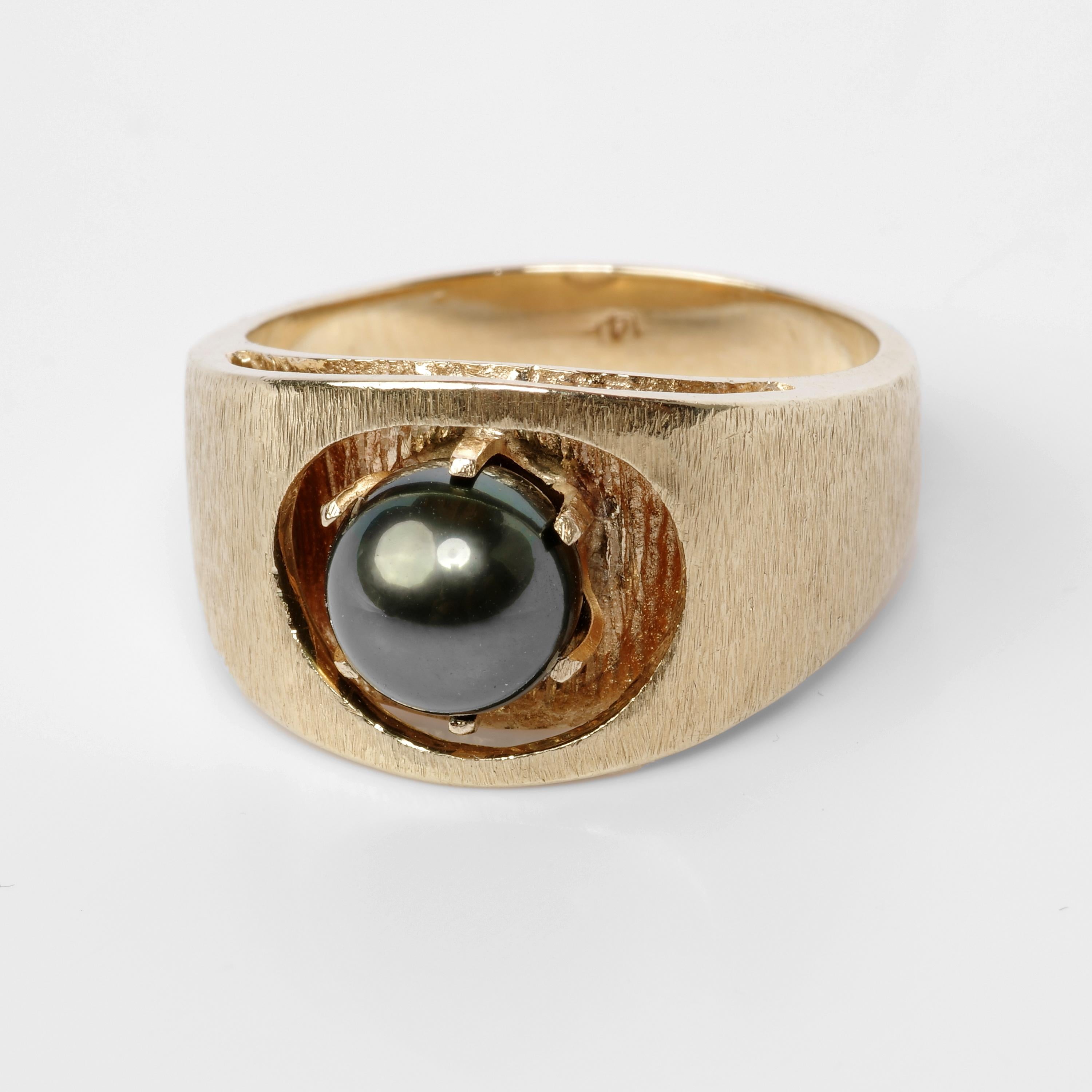 This circa 1970s men's ring was created in 14K yellow gold and features an 8.5mm cultured Tahitian pearl dramatically set into a lower-level platform and secured by six long prongs. From every angle, this ring is a work of dazzling Mid-century art.