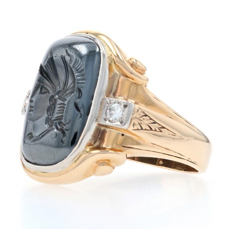 Bold yet refined, this ring will keep you looking sharp! Crafted in 10k yellow and white gold, this piece showcases a hematite intaglio featuring the profile of an ancient warrior wearing his helmet. Two milgrain-outlined natural diamonds flank the