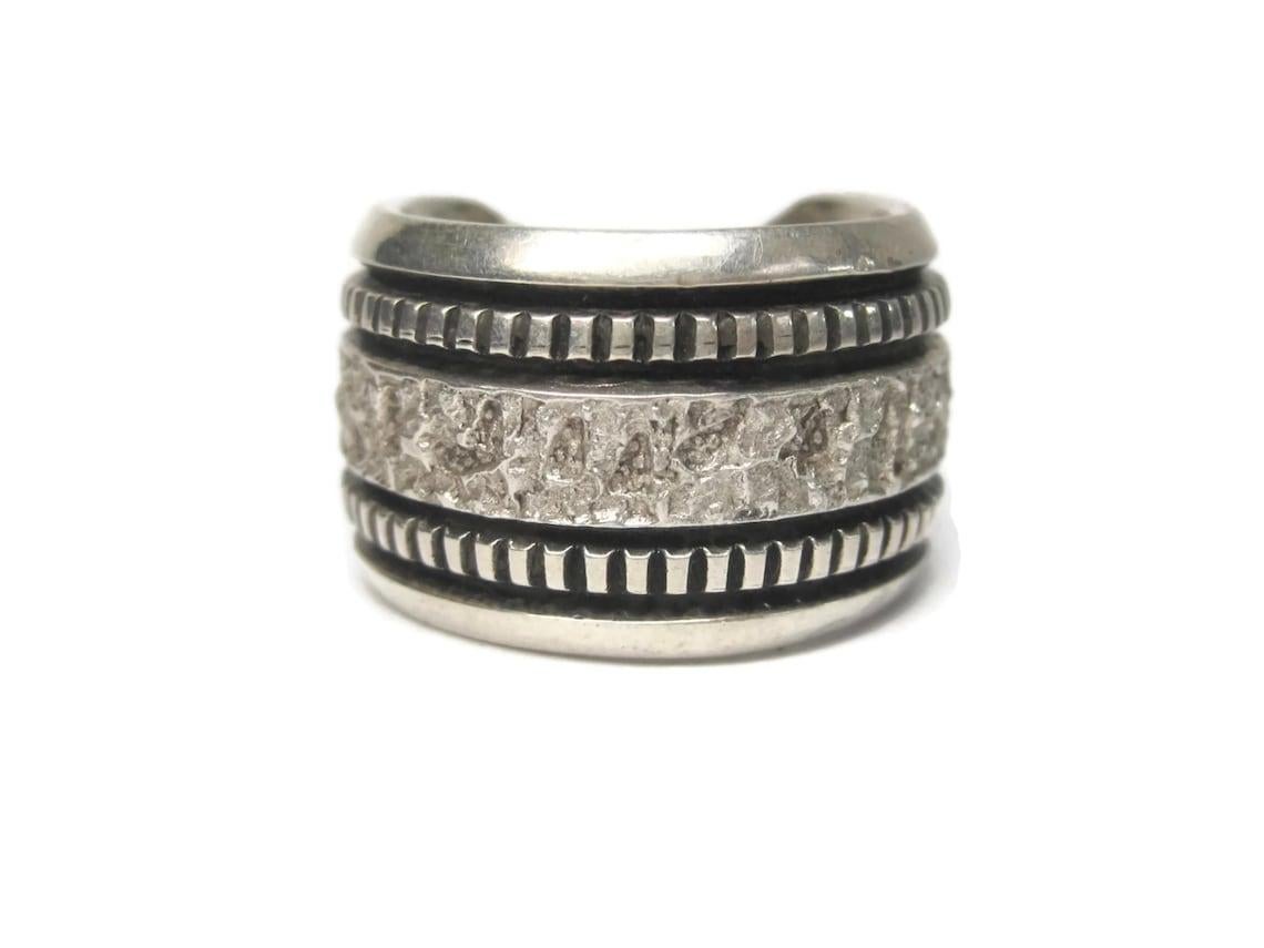 This gorgeous ring is the creation of Navajo silversmith Philbert Begay.
Phil is the son of famed silversmith Richard Begay.

This ring features 3 of Philbert's signature designs. The V shaped back, The textured middle and the overlaid 