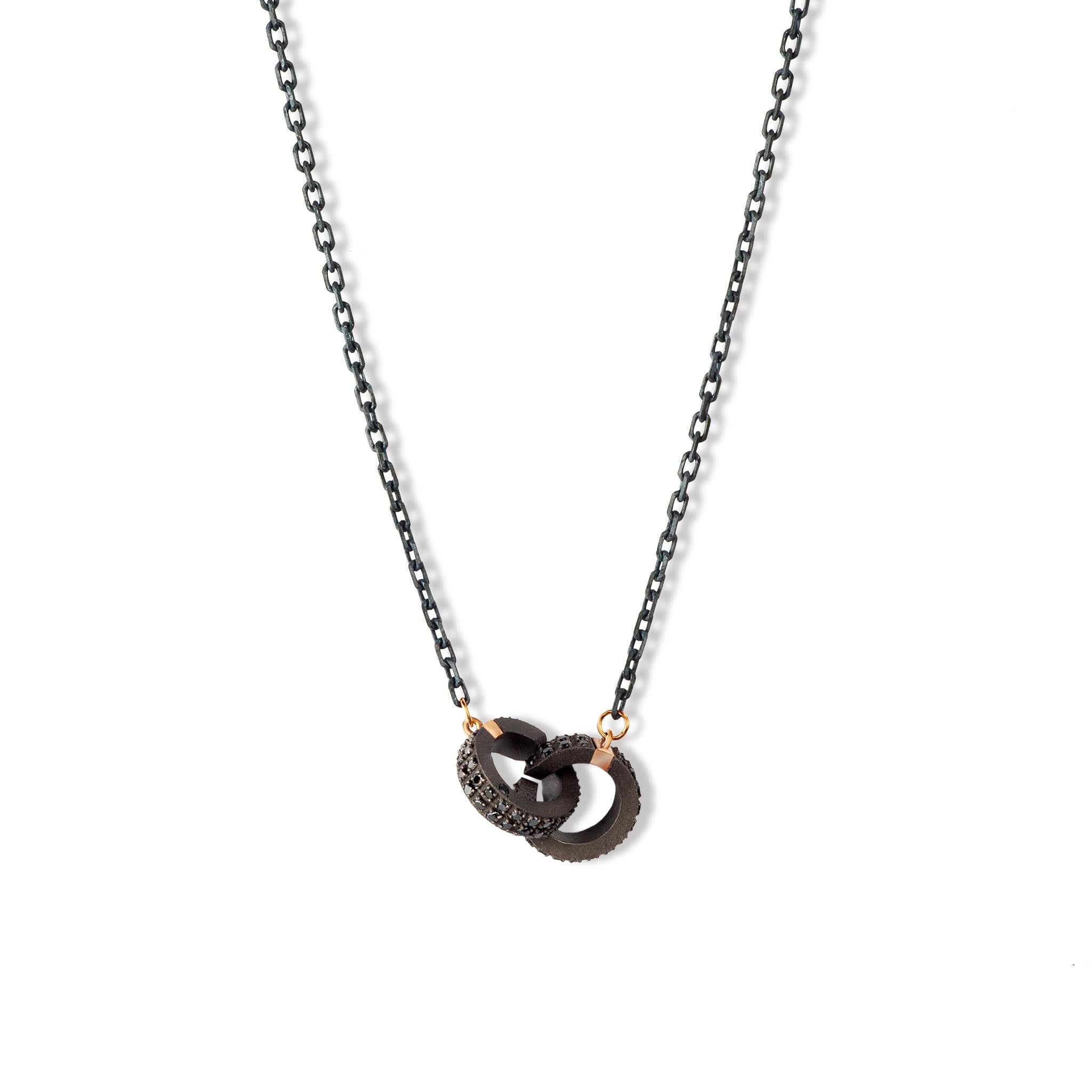 Men's necklace in titanium, 18 kt red gold, black diamonds and chain. The pendant, the necklace's main element, is made up of two titanium barrels hooked together but jointed. Completely covered with black diamonds, they both have two precious 18 kt