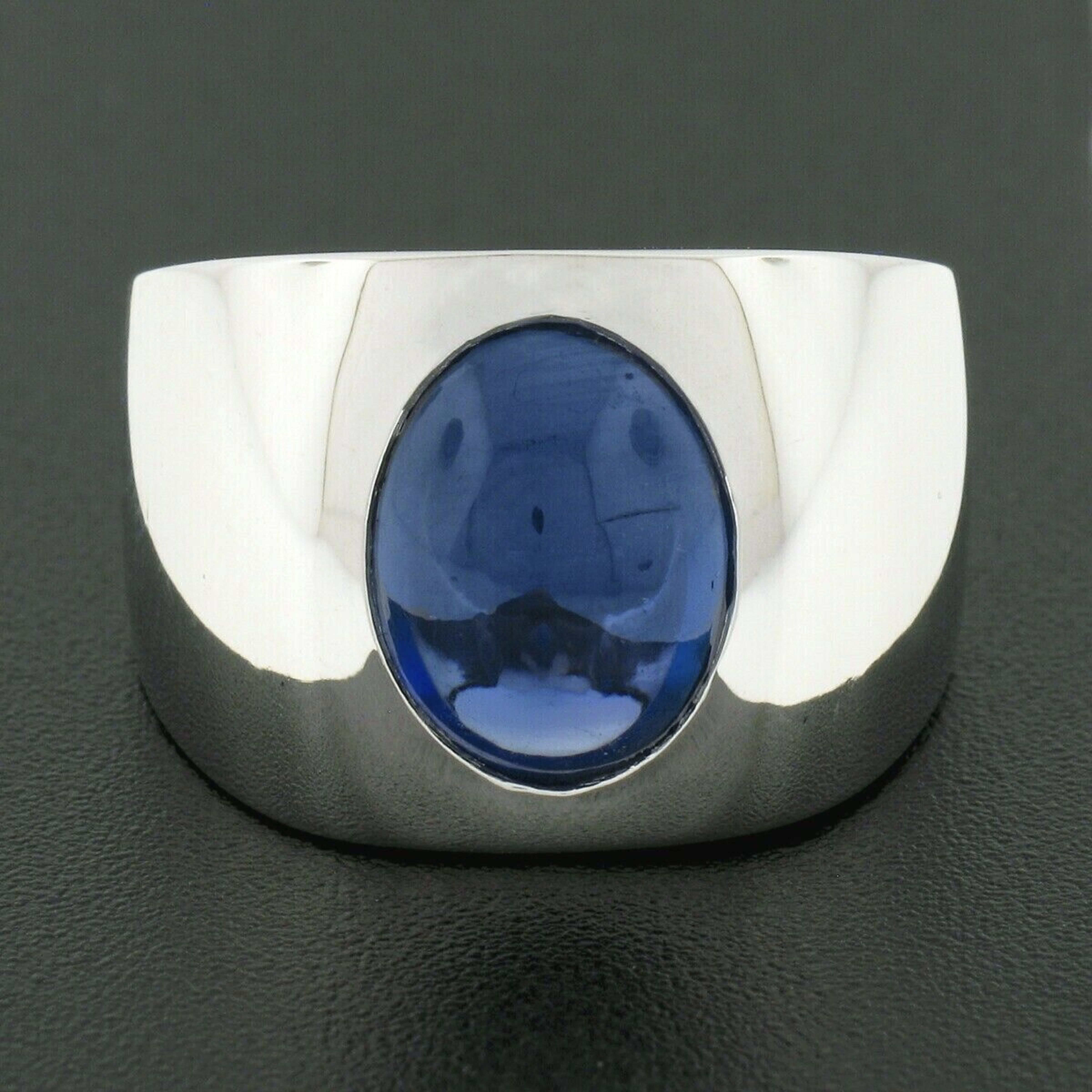 This large and very well made men's statement ring is newly crafted in solid platinum and features a magnificent, Gubelin certified, natural sapphire stone perfectly burnish flush set at its center. The oval cabochon cut sapphire is certified as