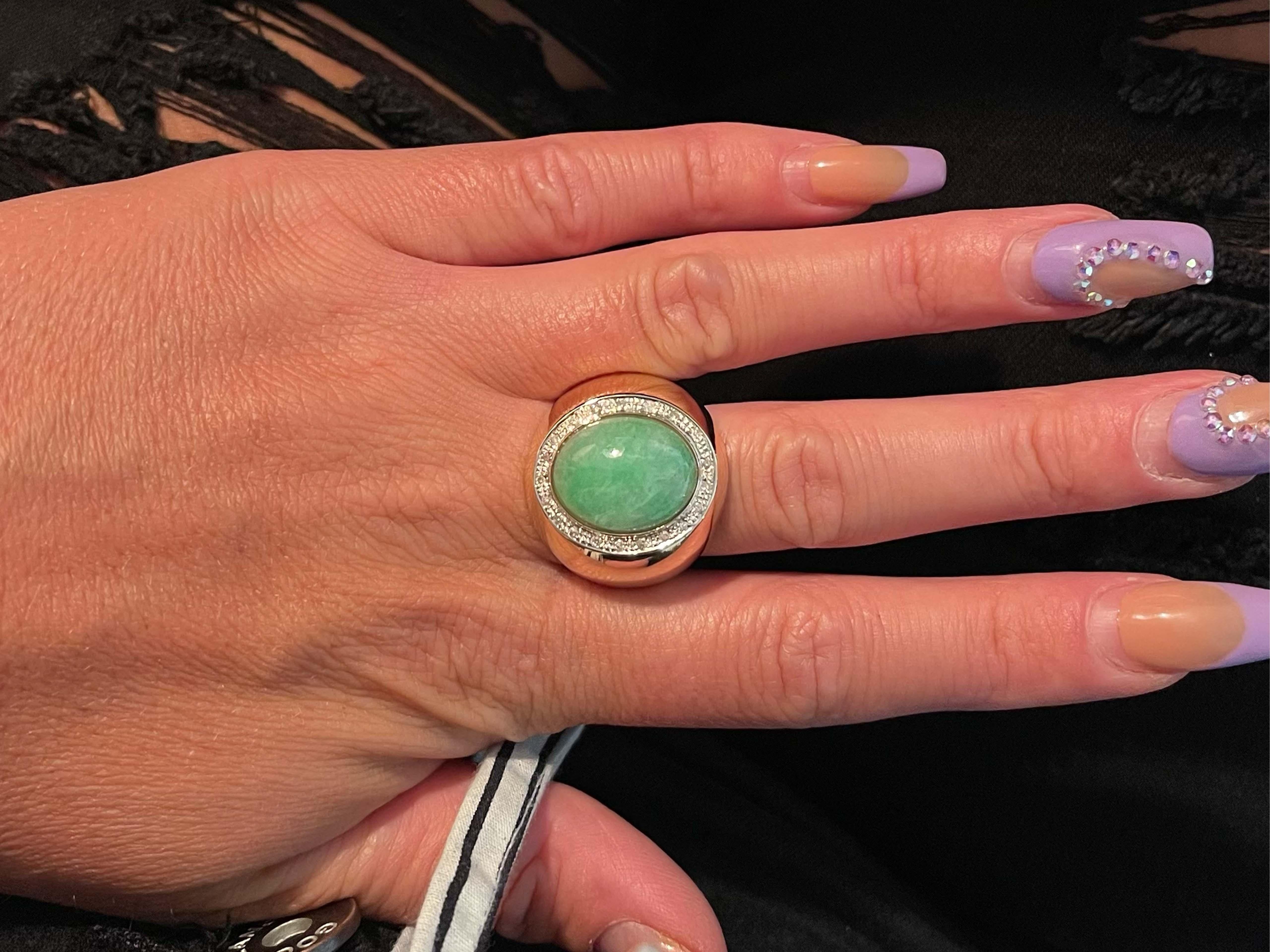 Men's Oval Light Green Jade and Diamond Halo Ring - 14k Yellow Gold. This stunning jade has a one-of-a-kind color. The Jade measures approximately 17.06 mm x 13.39 mm x 6.20 mm. The ring has a diamond halo of 20 diamonds. The diamonds total ~0.10