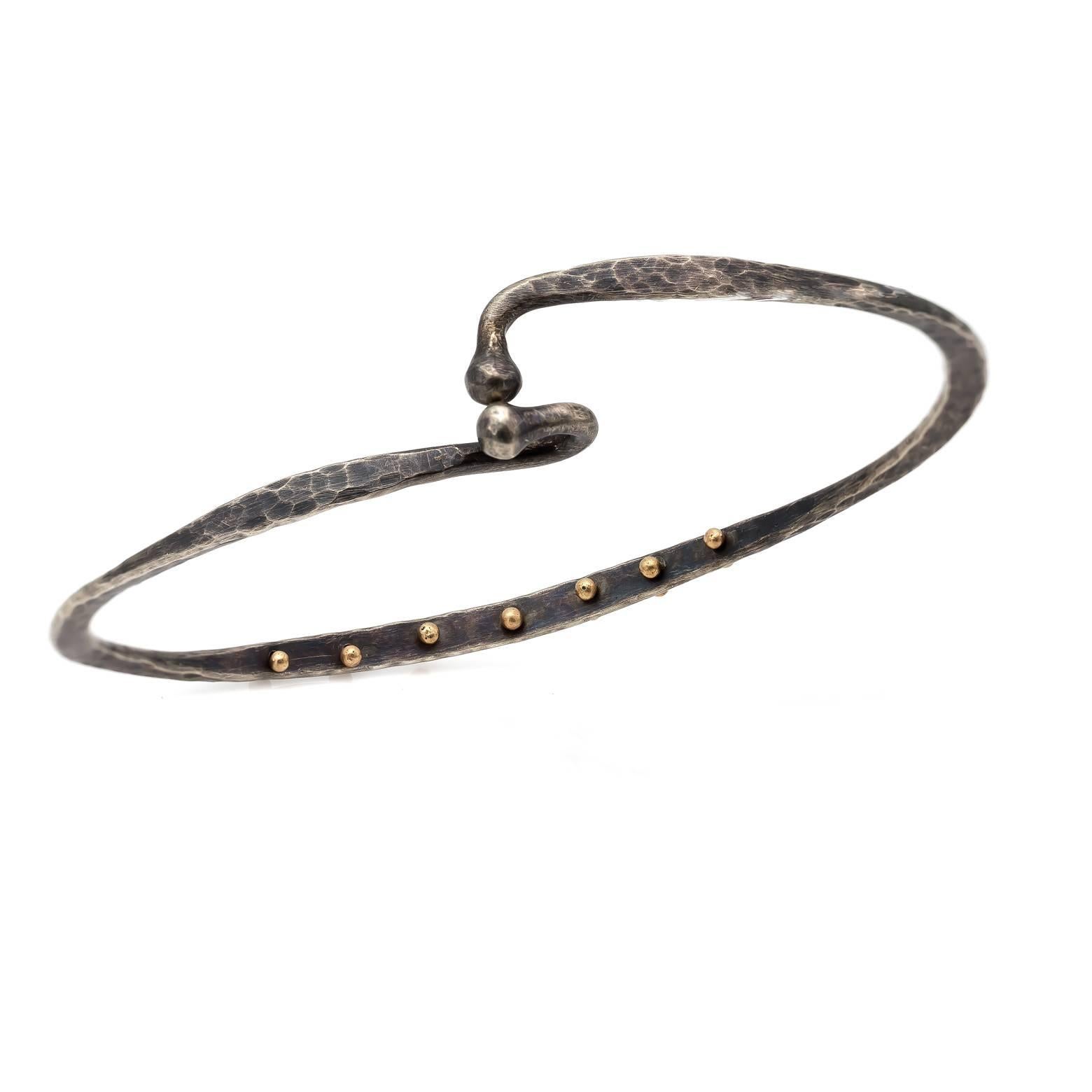 Artistic and chic this hammered cuff/bangle is adorned with 14K yellow gold studs that add a unique flare. The twisted and tapered design interconnects to hook together. A beautiful shade of grey. The bracelet opening measures 8