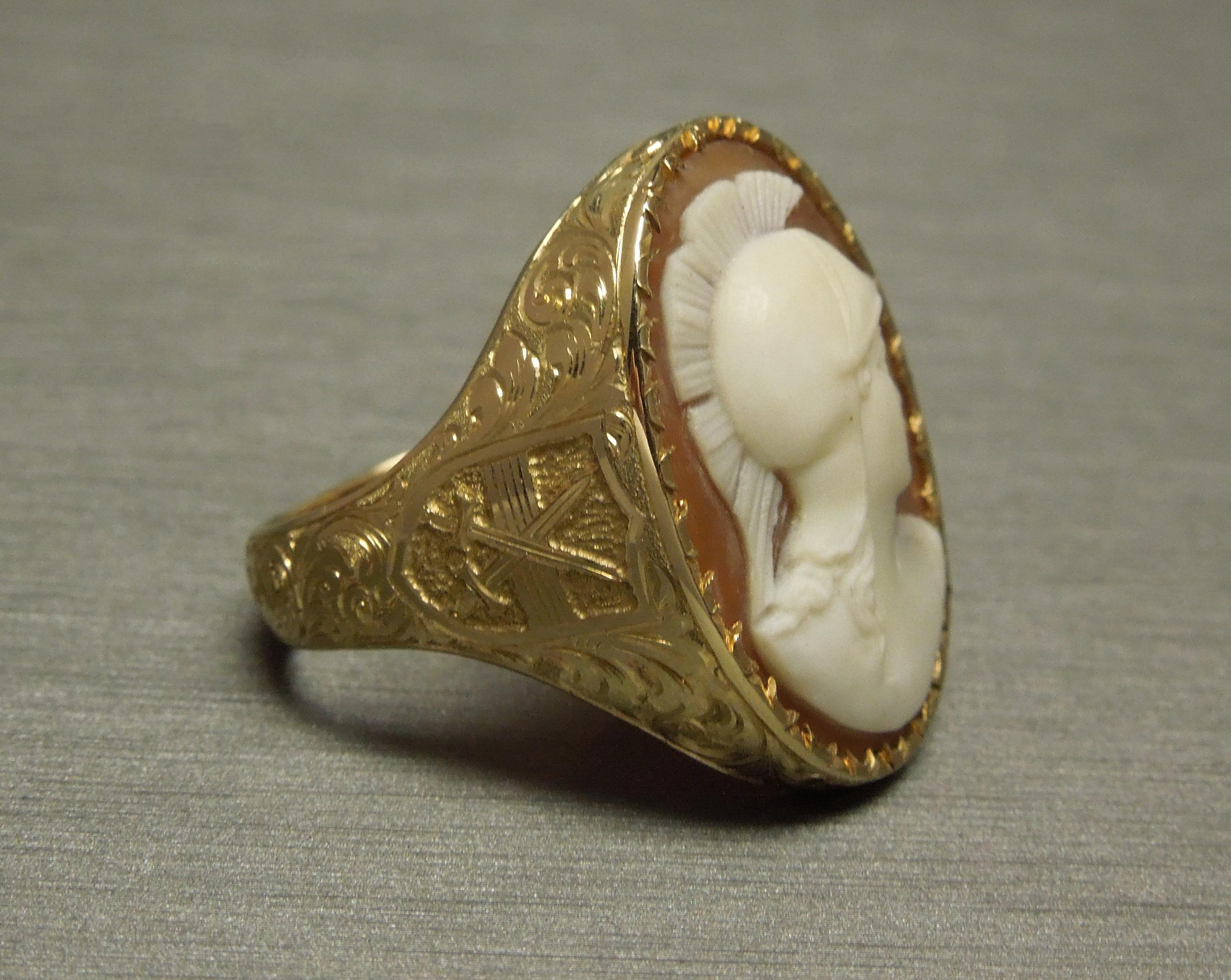 This period Men's Roman Warrior Cameo Ring contains a central Bezel set Conch Shell Cameo. Gold accented with intricately detailed Hand Engraving in Scroll designs with very fine detailing & Crossed Swords on each side. Very rare to find a man's