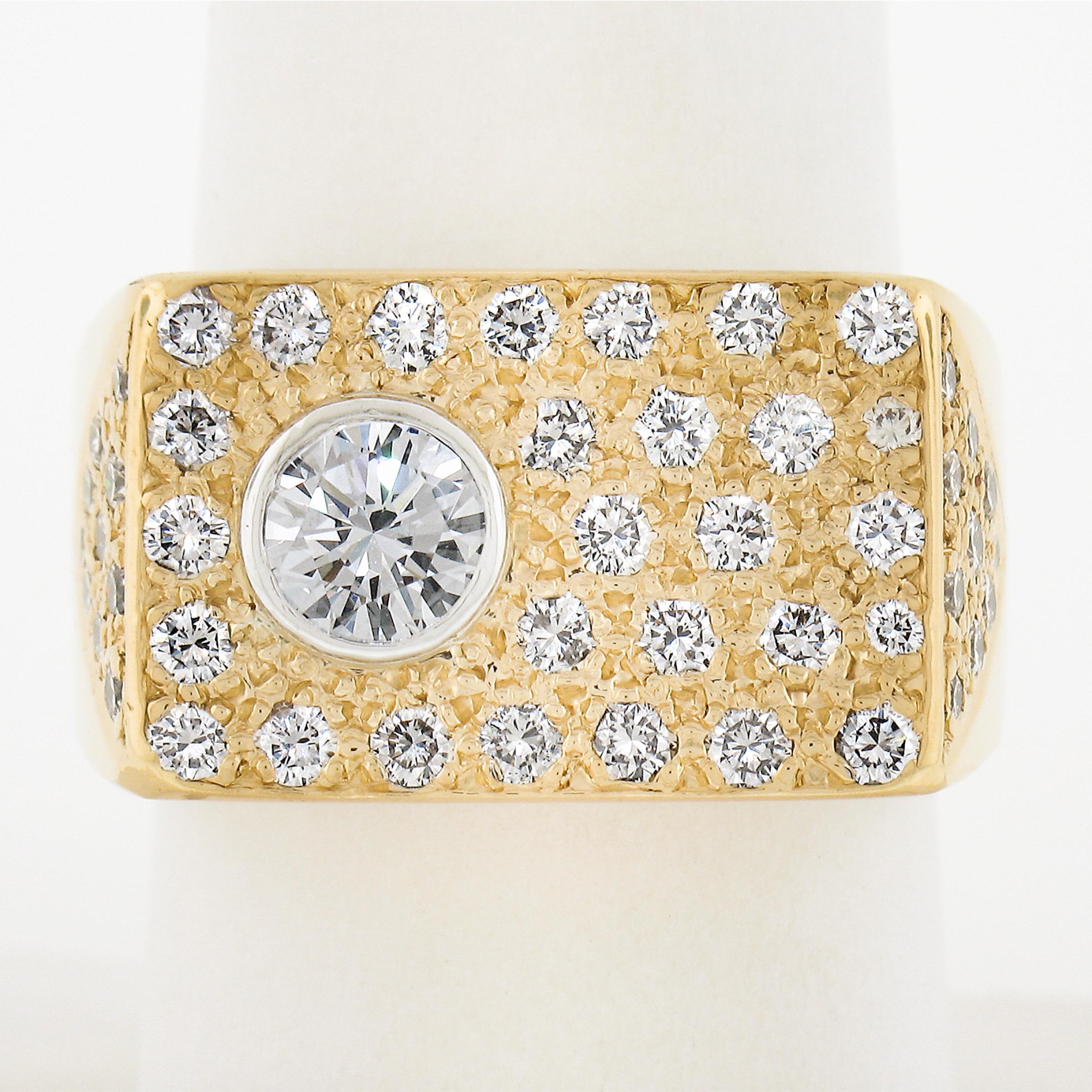 This men's geometric ring is crafted in solid 18k yellow gold and features a wide rectangular top adorned with 28 round brilliant cut diamonds across its top & part of the shoulders. There is 1 round brilliant diamond that is set in a bezel. The