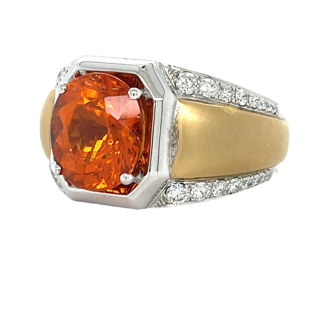 This unique Two Tone Men's ring has a vibrant oragne 12x11 mm Oval cut Spessartite (Orange Garnet) center stone. There are 32 brilliant cut round sparkling diamonds on the shank for the perfect accent. The ring is set in 14K white and yellow gold.