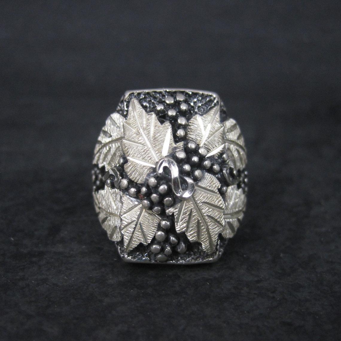 This gorgeous vintage black hills silver ring bears the classic leaf and grape design.

The face of this ring measures 15/16 of an inch north to south.
Size: 9
Weight: 15.7 grams

Condition: 90s dead stock
