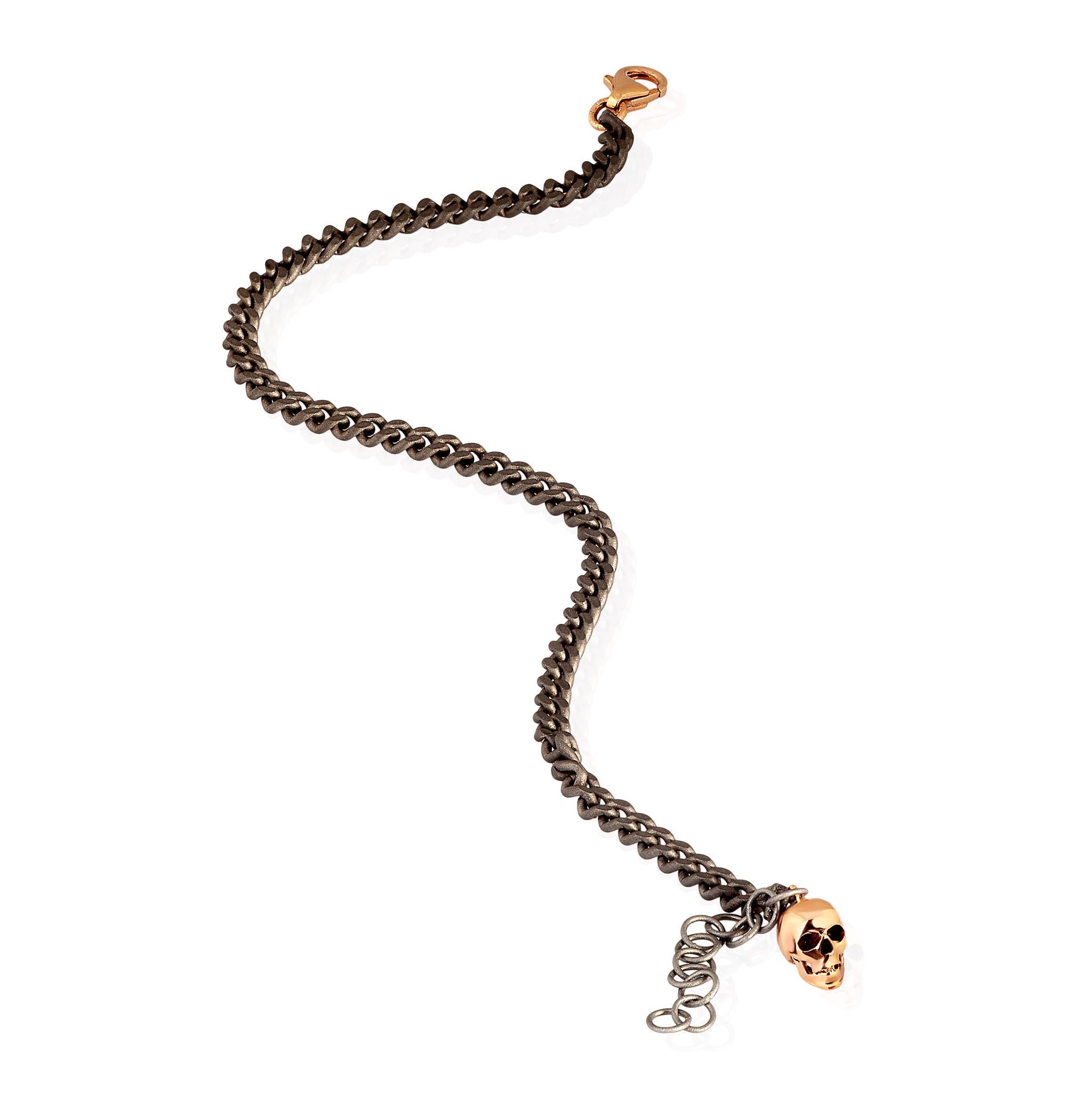 Men's titanium bracelet, 9 kt rose gold clasp and 9 kt red gold skull. The fine groumette chain is the main element of the bracelet, which ends with a precious 9kt rose gold hook clasp and a charming red gold skull pendant on the 9kt rose gold ring.