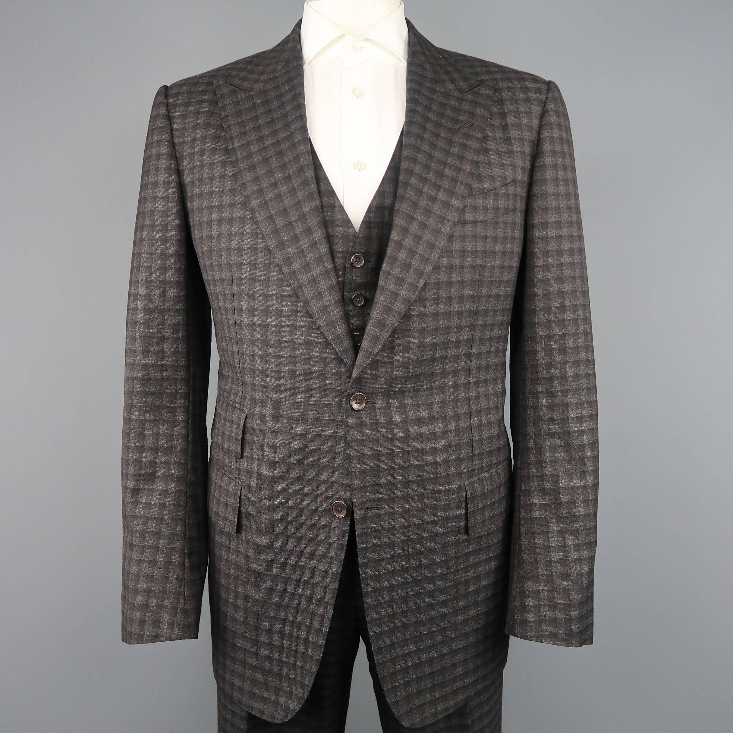 Three piece TOM FORD suit comes in charcoal and taupe checkered plaid wool and includes a single breasted, two button sport coat with wide peak lapel and functional button cuffs, V neck vest, and flat front, cuffed hem trousers with side tabs. Made
