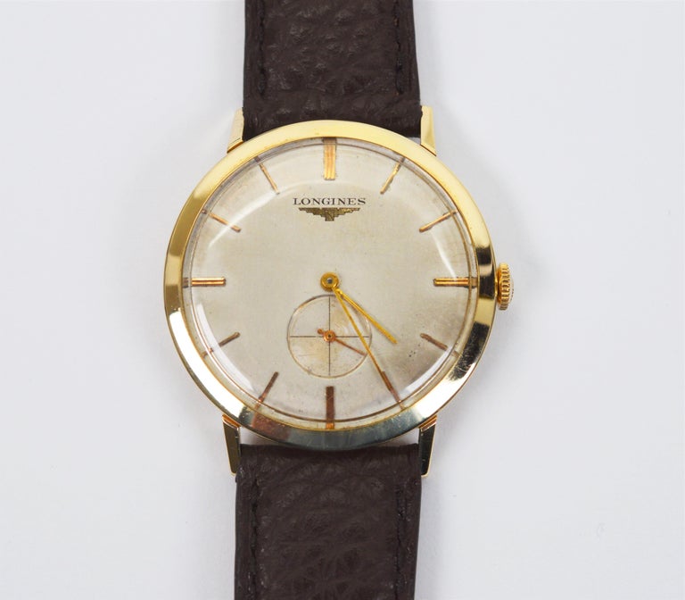Circa Post War, 1950s Longines Men's Wrist Watch with Swiss 17 jeweled manual wind movement. The fabulous '50's era watch has a fourteen karat 14k yellow gold case in size 32mm with original silver-toned dial and matchstick numeral markers and sub