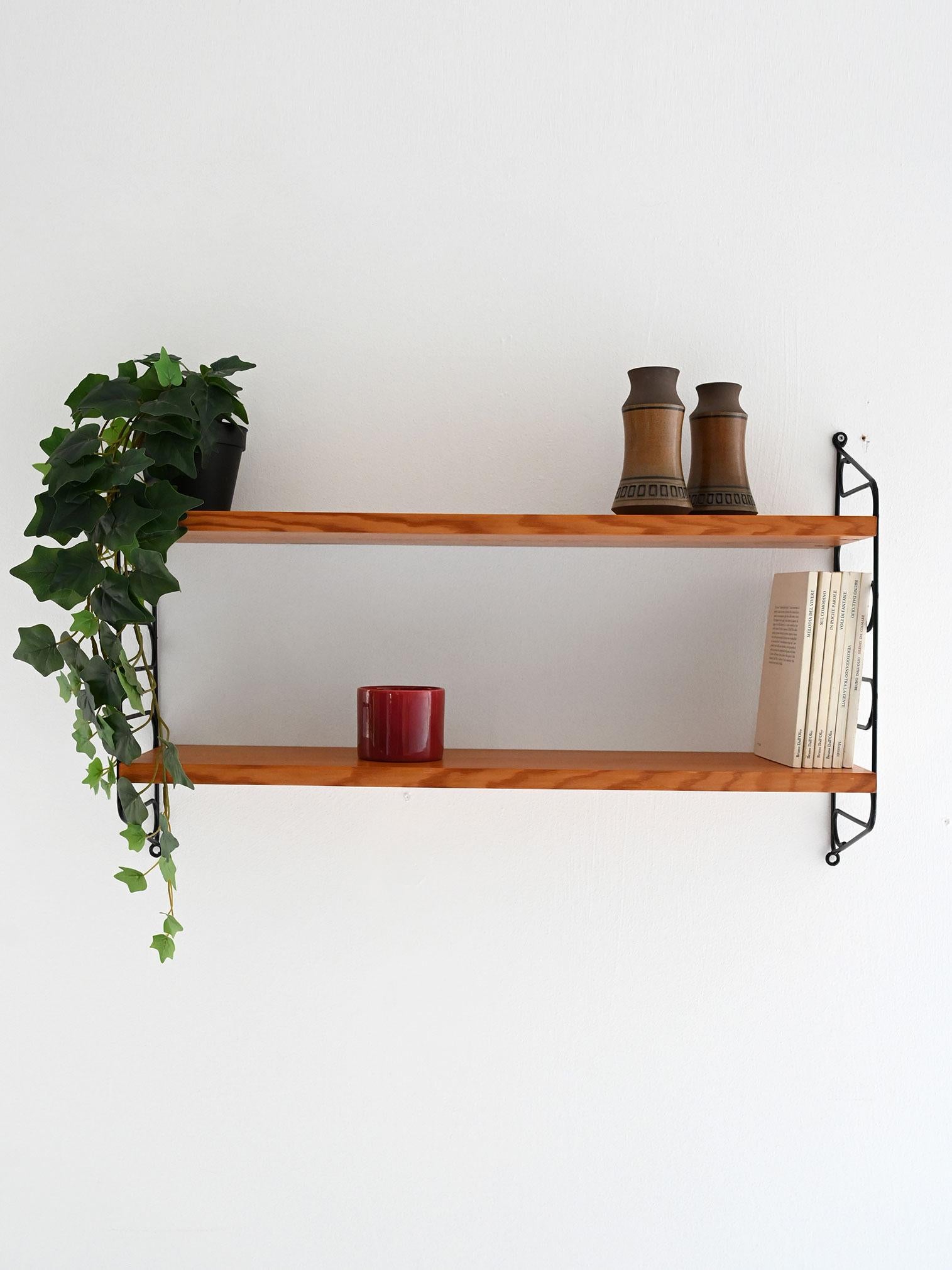 Mensola a muro vintage con due ripiani in teak e struttura in metallo nero decorata con motivo ondulato.

Sistema di mensole a muro “Hylla” di produzione scandinava anni ’60. Composto da due ripiani in teak e struttura laterale in metallo verniciato