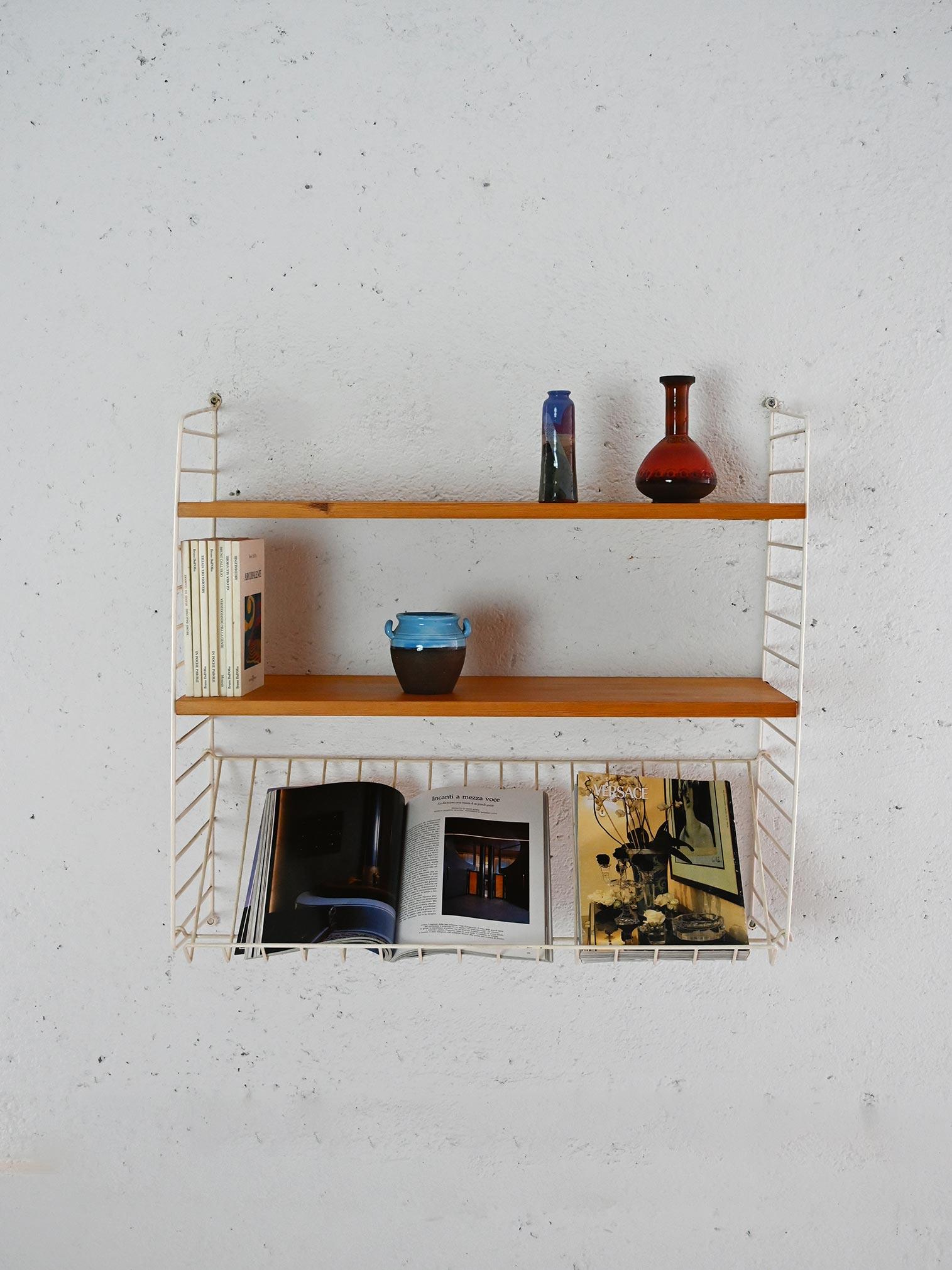 Scandinavian wall shelving system consisting of 2 mahogany wood shelves and white coated metal support structure.

In addition to serving as a stand, the metal frame provides an additional sloping shelf, perfect for displaying catalogs or magazines.