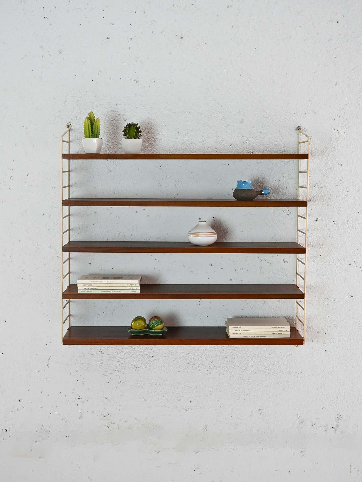 1960s wall-mounted bookcase with 5 wooden shelves and white metal frame. 

Perfect for minimalist settings, its open structure enhances the space without weighing it down, offering versatility and functionality for displaying books, decorative