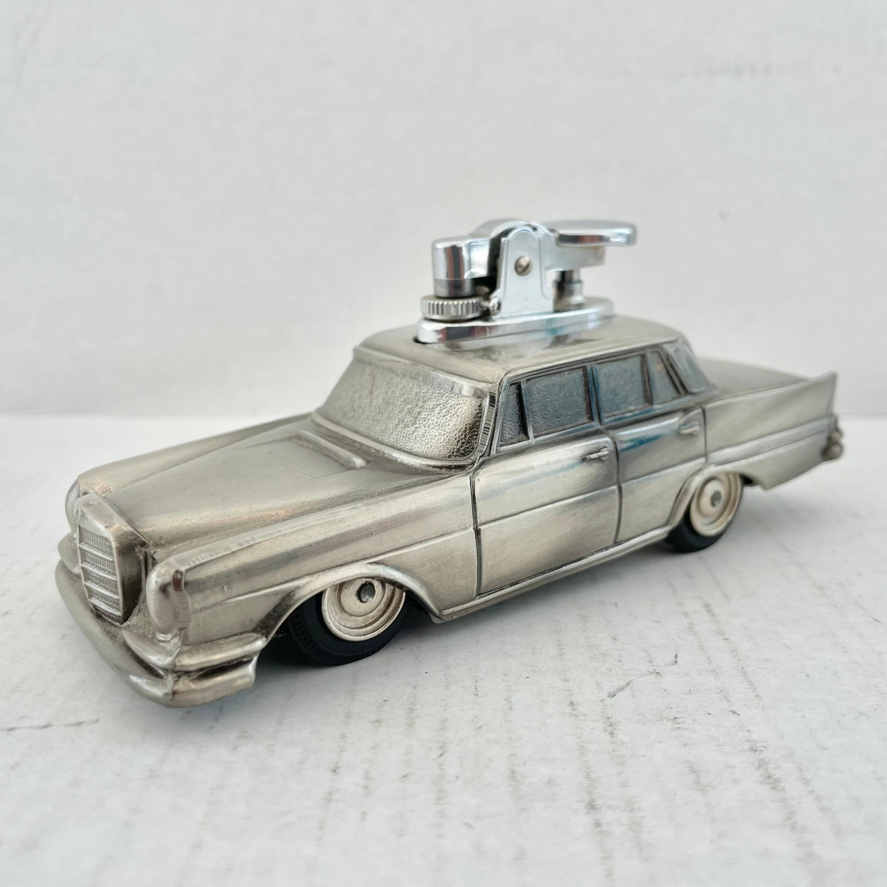 Cool vintage table lighter in the shape of a Mercedes Benz sedan. Made in Japan, 1980s. This piece has great balance and details like rubber wheels that roll. Mercedes logo on the front and back and a 'Made In Japan' sticker on the underside as well