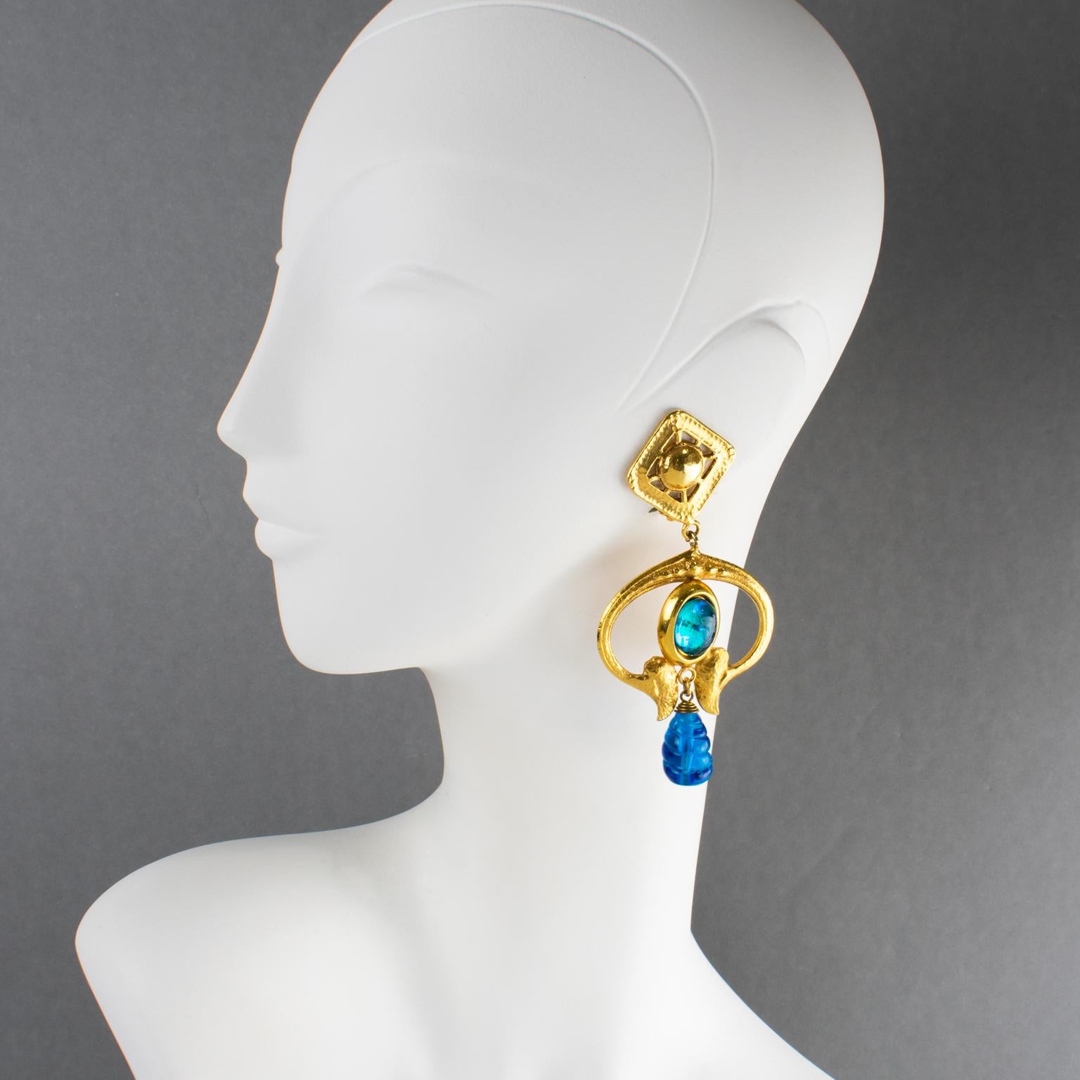 Mercedes Robirosa Paris ha disegnato questi orecchini lunghi a clip ultra-chic. I pezzi vantano uno stile barocco penzolante con volute di metallo dorato ed elementi geometrici completati da gocce di vetro colato intagliato e cabochon di vetro