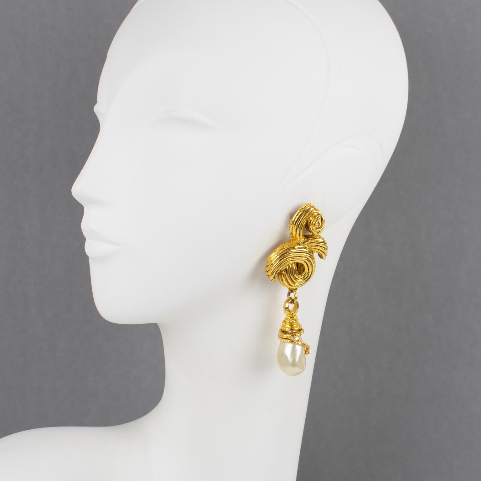 These ultra-chic Mercedes Robirosa Paris massive clip-on earrings feature a dangling baroque style with swirling and teardrop. The gilt metal framing is all textured and complimented with pearl-like poured glass drops. Each piece is signed with the