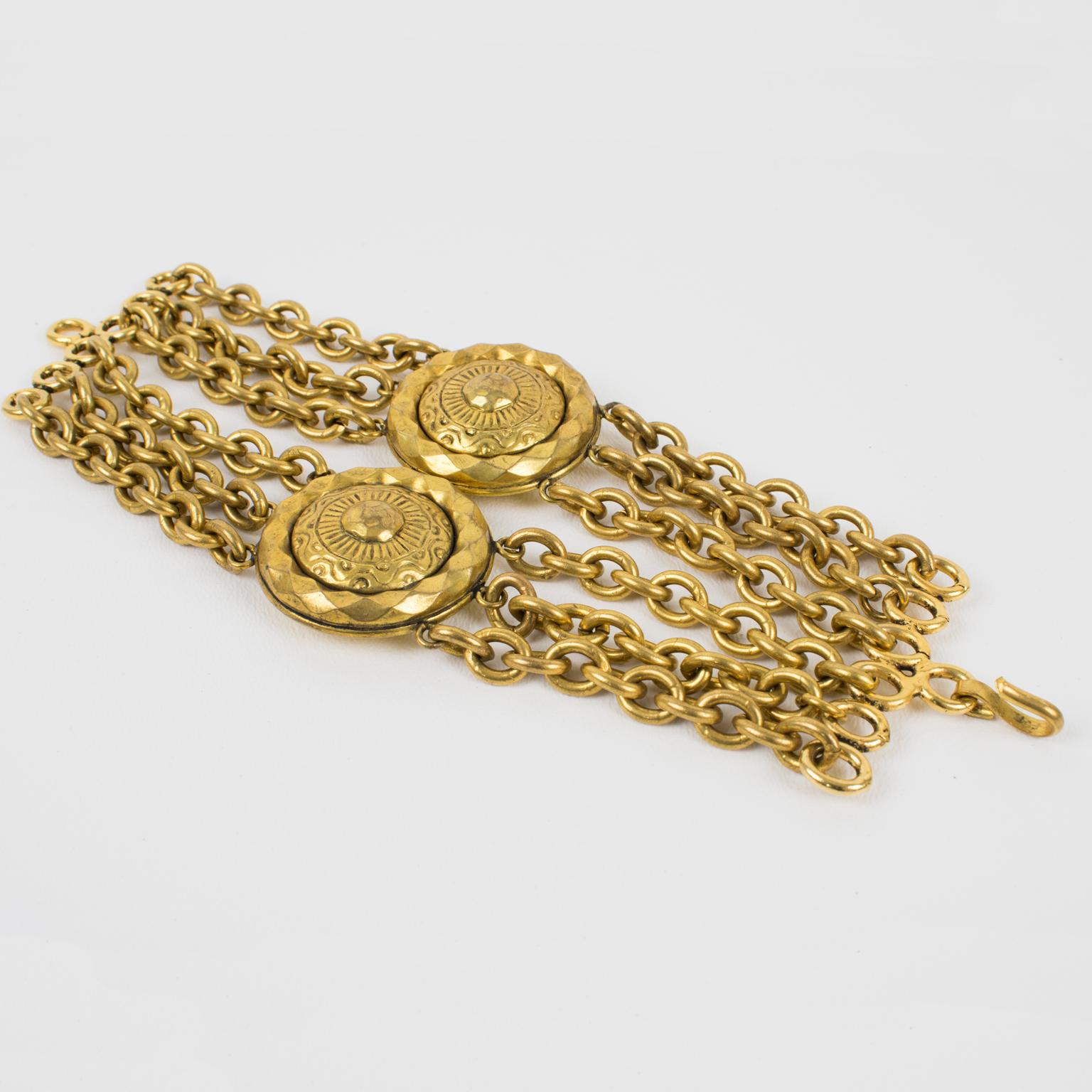 Ce superbe bracelet à maillons Mercedes Robirosa Paris présente un design multi-chaînes en métal doré antique de forme massive, complété par deux grands médaillons sculptés. Le bracelet est signé au dos avec le logo de la marque Robirosa. 
Le