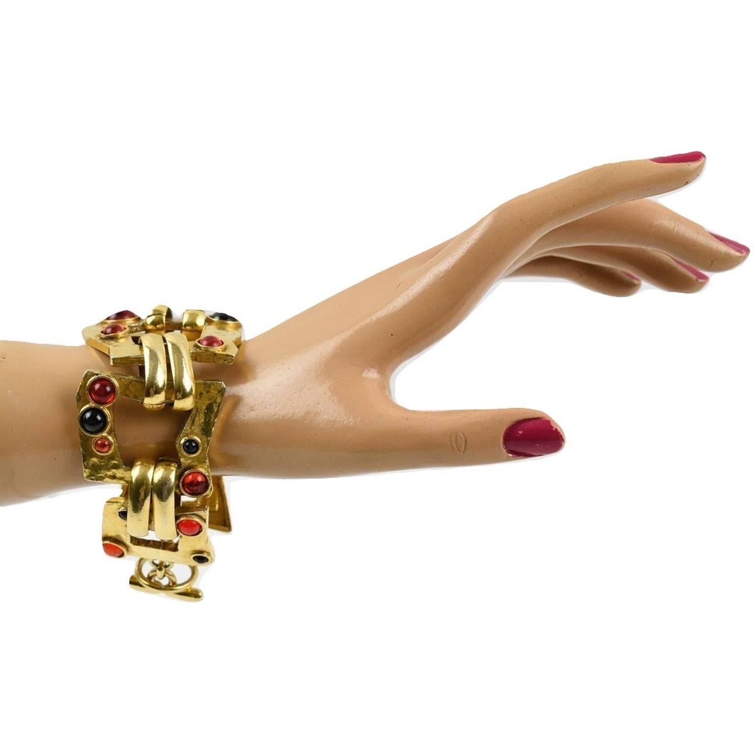 Very chic Mercedes Robirosa Paris link bracelet. Modernist fantasy style with gilt metal all textured and pierced, ornate with red and black Gripoix poured glass cabochons. There is a toggle closing clasp, and each link has a signature at the