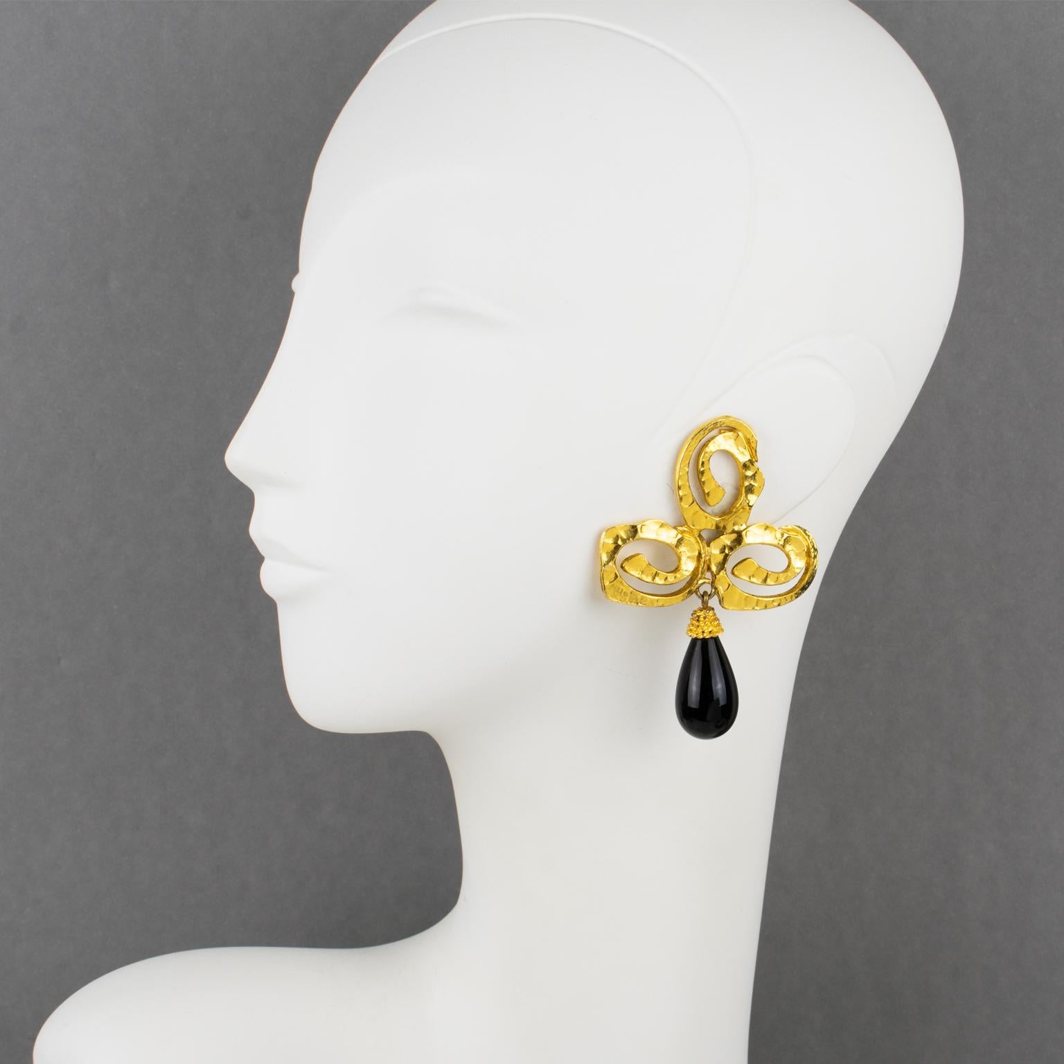 These ultra-chic Mercedes Robirosa Paris clip-on earrings feature a dangling baroque design with stylized clover and teardrop. The gilt metal is textured and complemented with black poured glass cabochon drops. The clips are signed at the back with