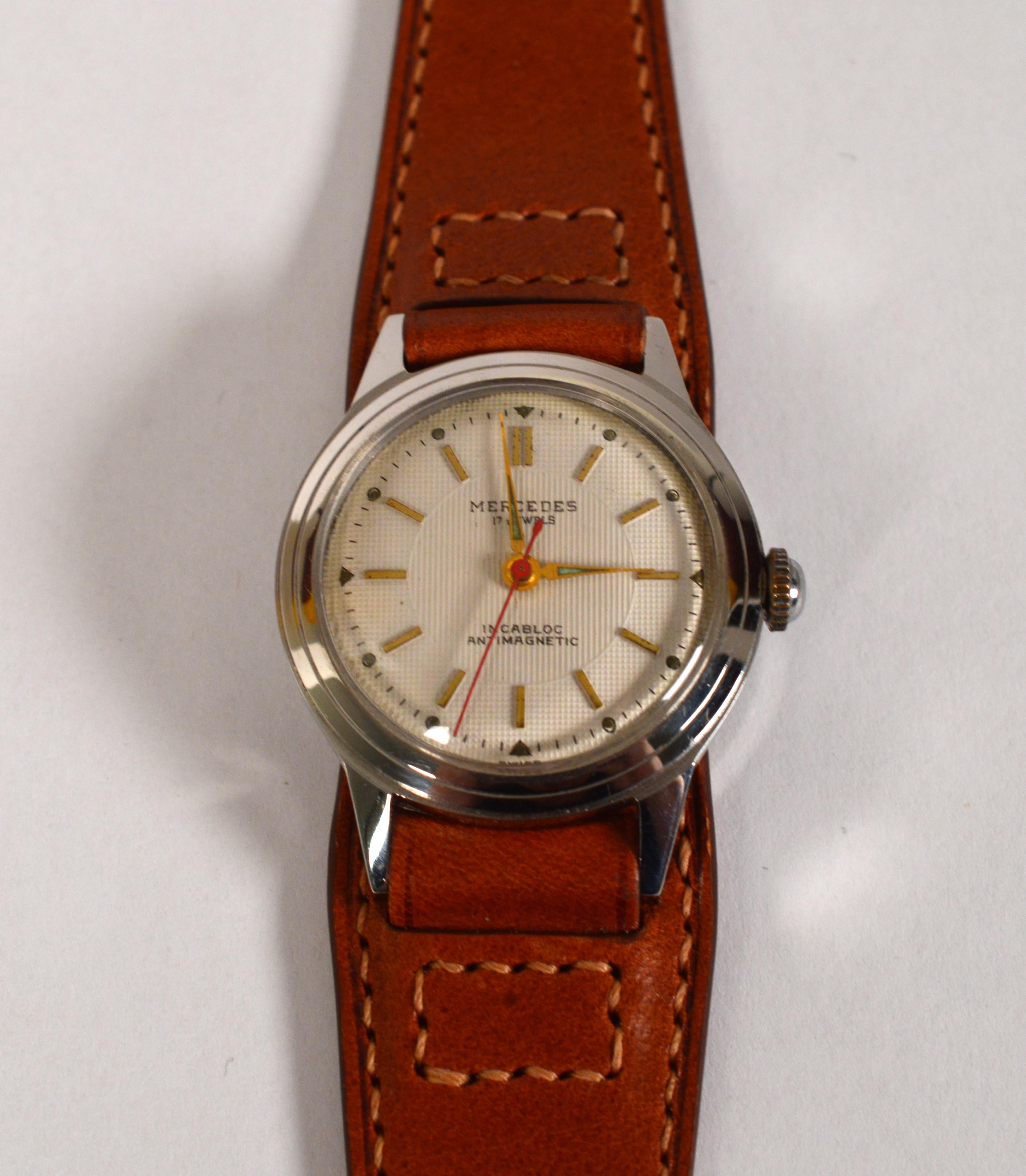 In mint condition, enjoy this post WWII Style Mercedes Winder 32mm Men's Wrist Watch. With a pristine linen face, the gold tone hands and matchstick indexes are sleek and easy to read with the red second hand as a nice compliment. This Mercedes has 