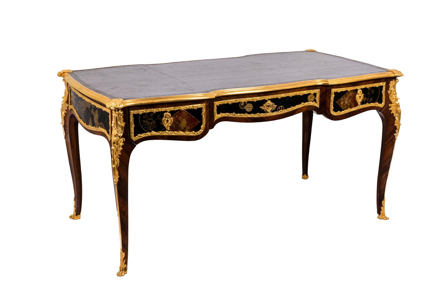 Flat desk of Louis XV style in rosewood veneer and chiseled and gilded bronze, opening with three drawers on the front. Tray covered with black leather morocco adorned with a frieze. Ornamentations adorned with shells and acanthus leaves. The belt