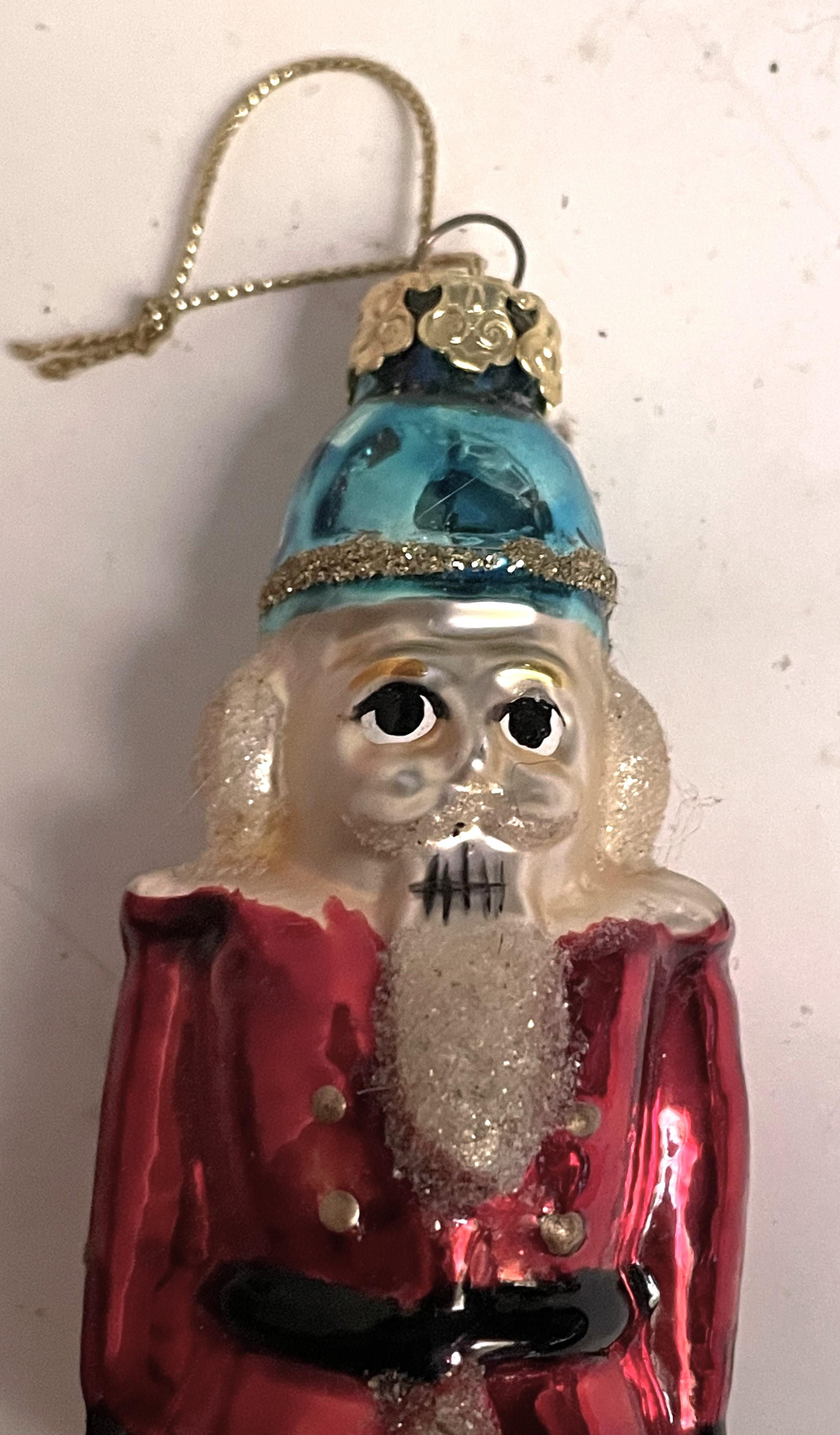 Questo è il più simpatico ornamento per l'albero di Natale del Soldato Schiaccianoci, realizzato in vetro soffiato. An He ha una finitura che ricorda la pelliccia nella parte inferiore del mantello, sulla barba e sulle orecchie (manicotti), una