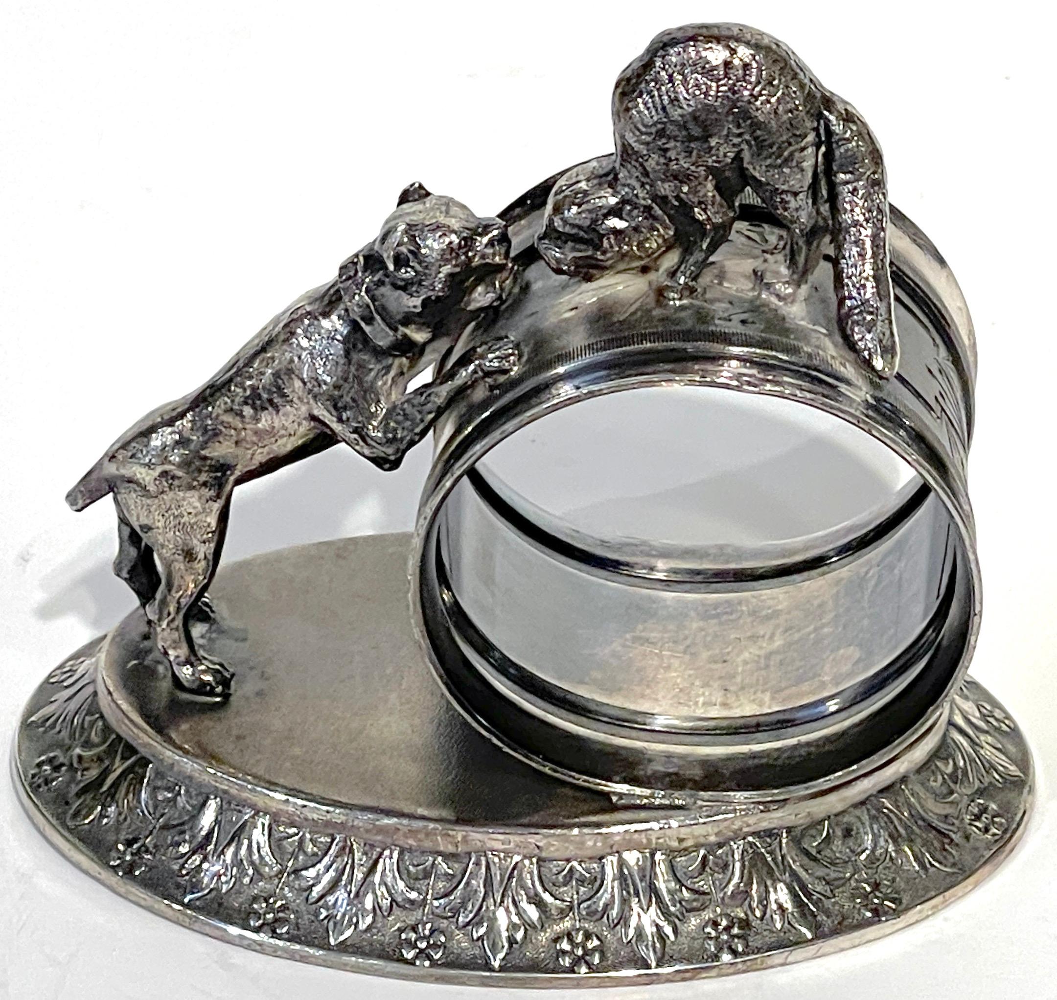 Meriden 'Dog and Cat' Silverplated Figural Napkin Ring
USA, Circa 1890

Offering an exquisite Meriden 'Dog and Cat' Silverplated Figural Napkin Ring from the USA, circa 1890. This charming piece portrays a dog standing on a 3.5 x 2.5 oval base, its