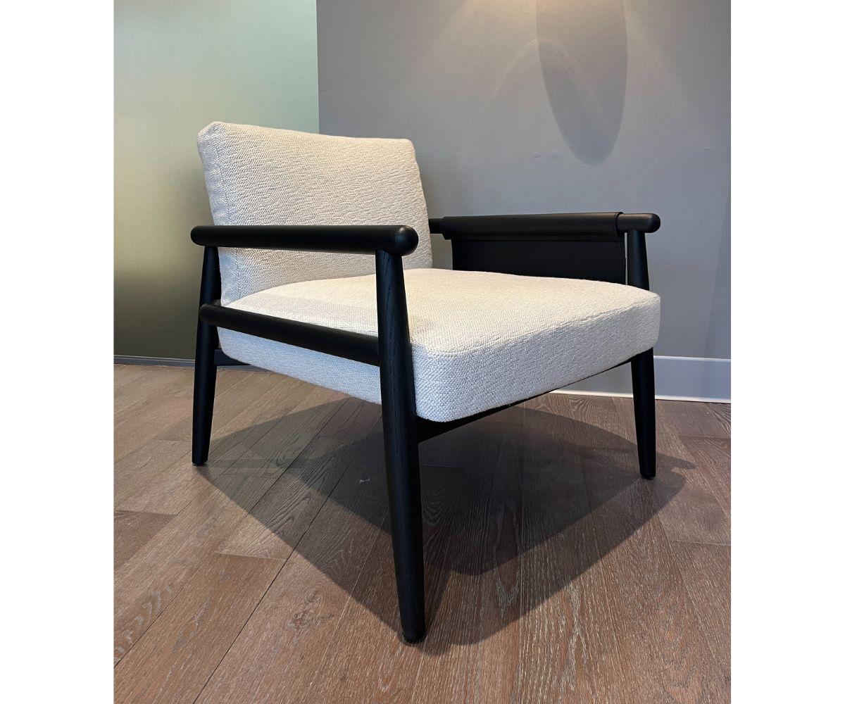 The Meridiani Teresa armchair, designed by Andrea Parisio, features essential lines accentuated by the warmth and solidity of skillfully crafted oak wood. The black oak frame is paired with a black saddle-leather body, defining the back, armrests,