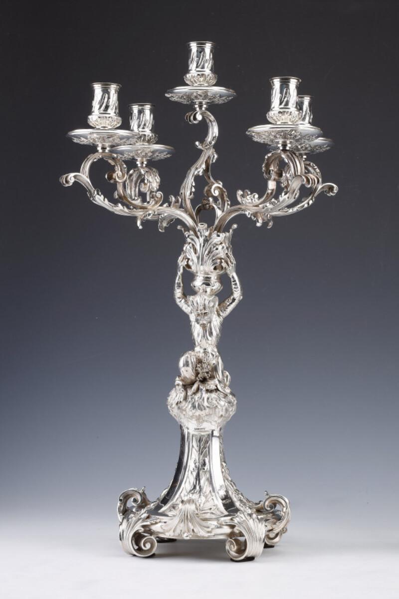 Important pair of candelabras with five sconces in solid silver with foliage decoration. The central bouquet is supported by a monkey standing on a circular base decorated with reeds and plants in reserves.

Dimensions: height 53 cm – width 34 cm –