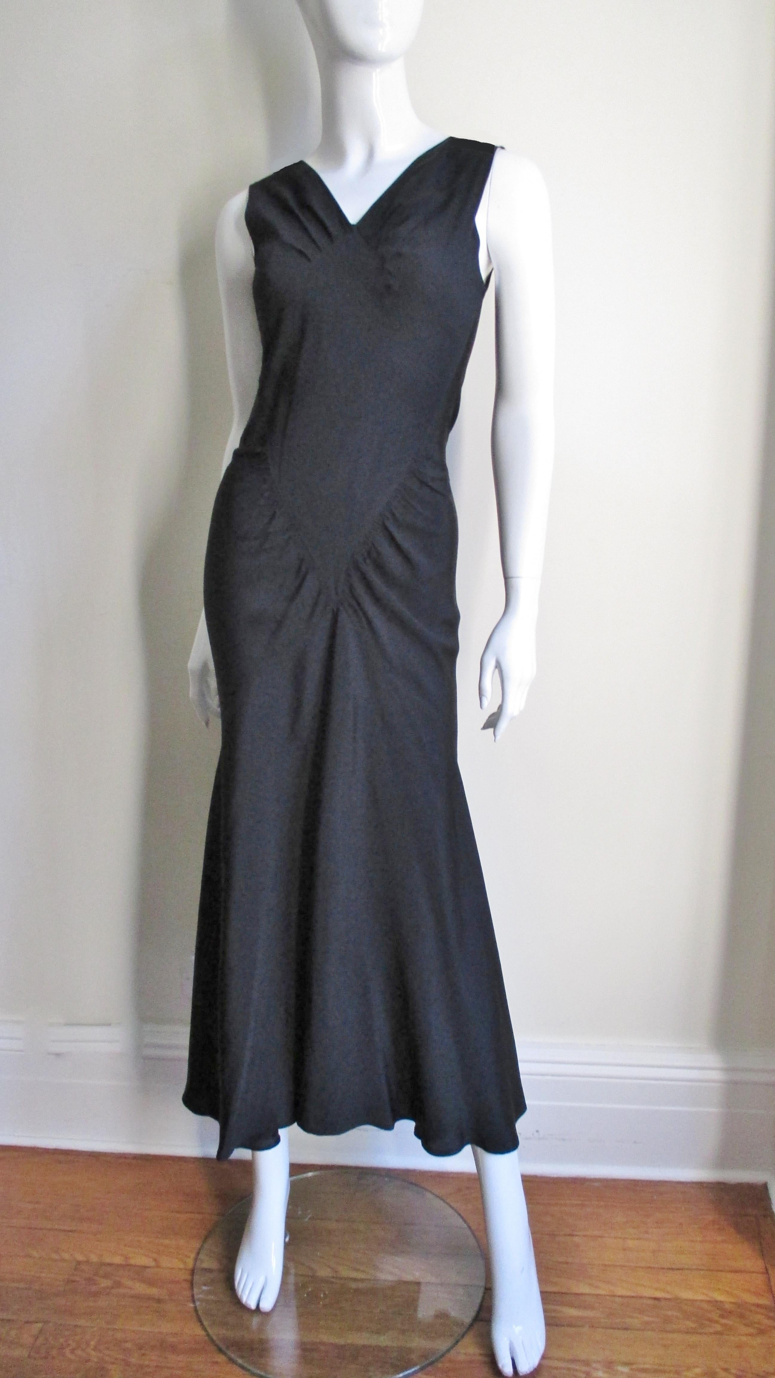 Ein schwarzes Seidenkleid aus den 1930er Jahren mit unglaublichen Nähten und Linien.  Das Kleid umspielt den Körper mit einem vorderen V-Ausschnitt und rautenförmigen Einsätzen und läuft dann zum handgenähten Saum aus.  Dazu gehört ein weißer Bolero